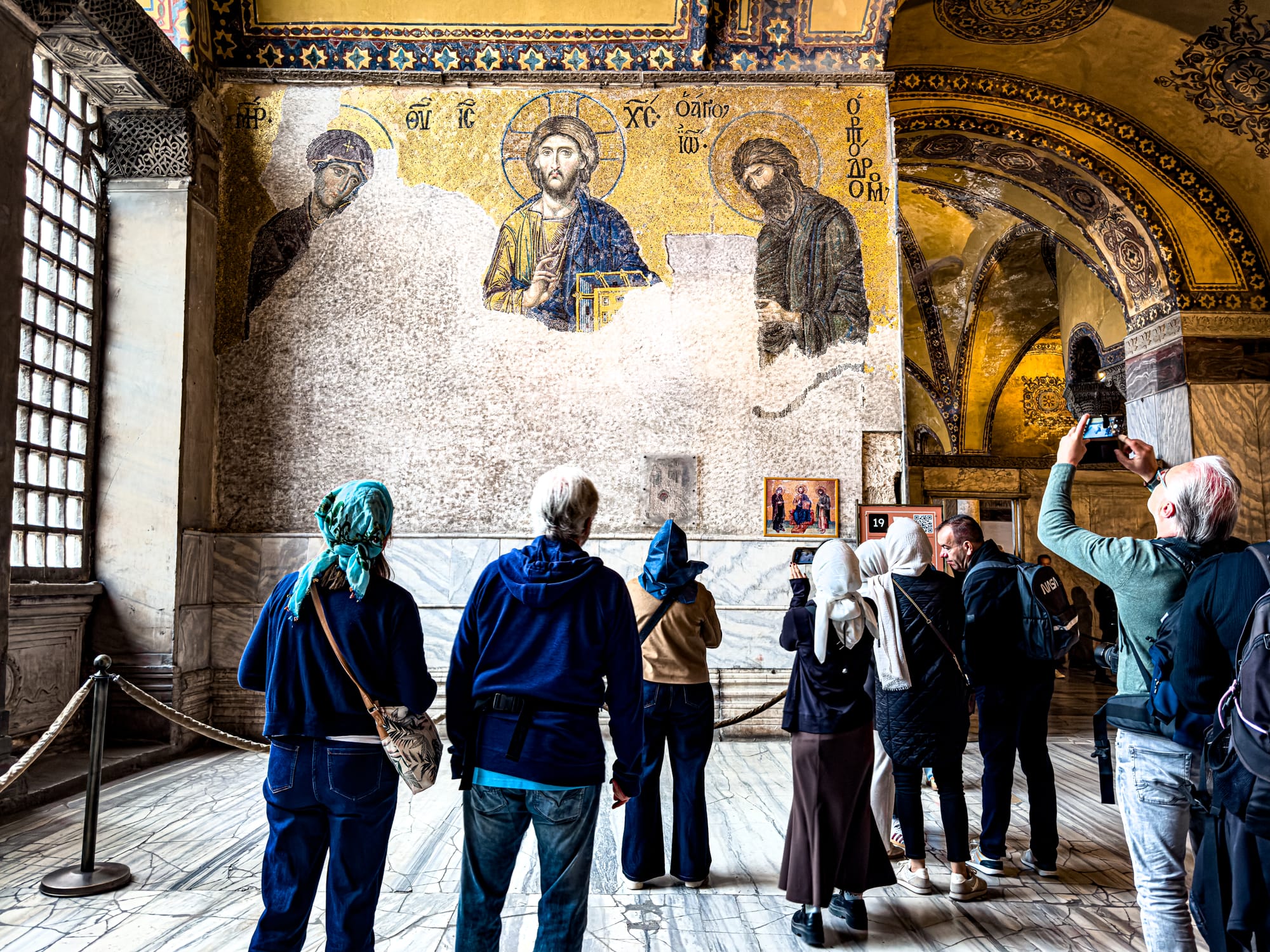 Visitors gather to admire a partially preserved golden Byzantine mosaic of Christ at Hagia Sophia