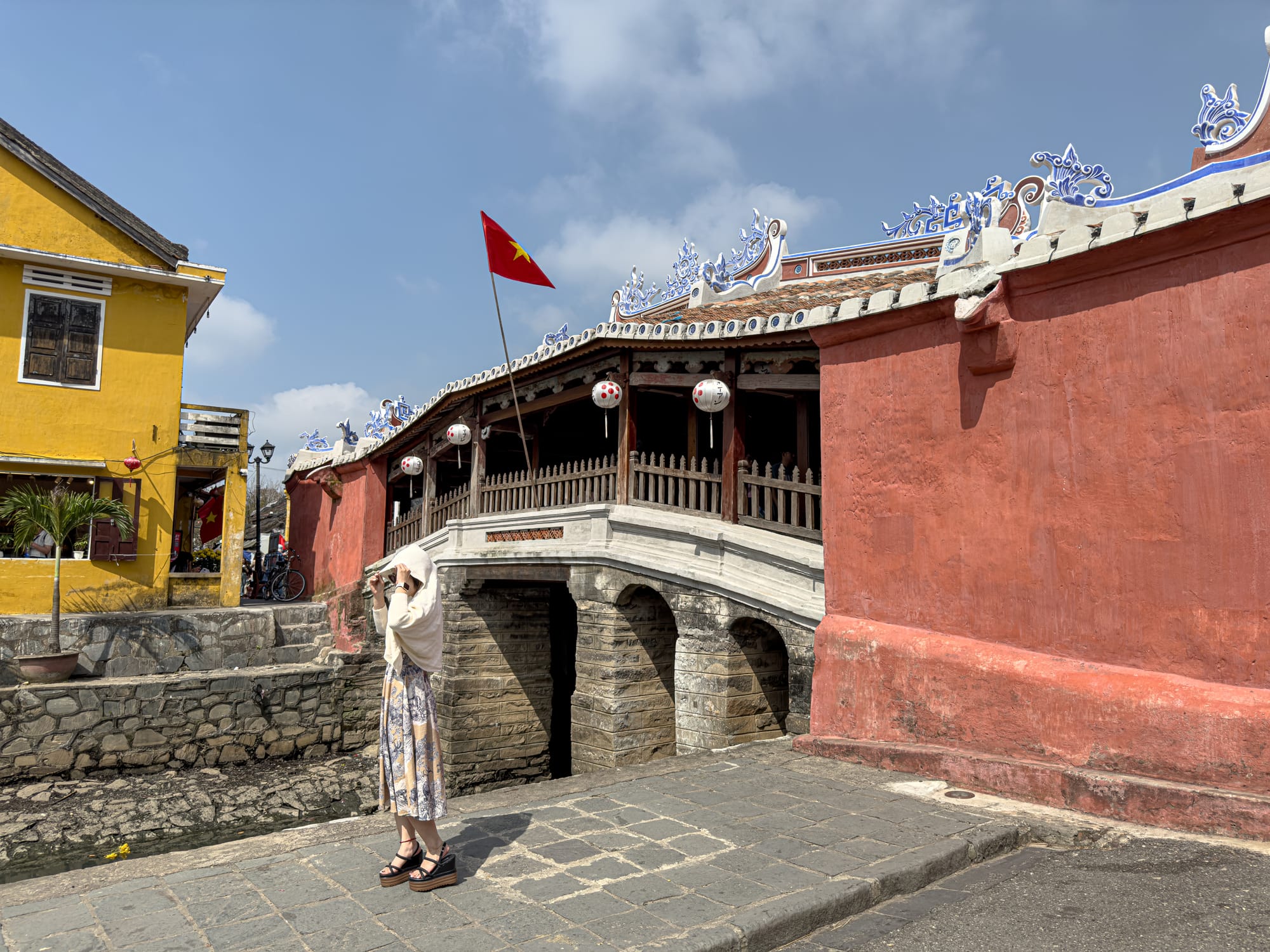 The 16th-century Japanese Covered Bridge in Hội An’s Old Town, Vietnam, with its red walls, ornate roof decorations, and stone foundation, symbolizing the town’s historic Japanese community and cultural heritage