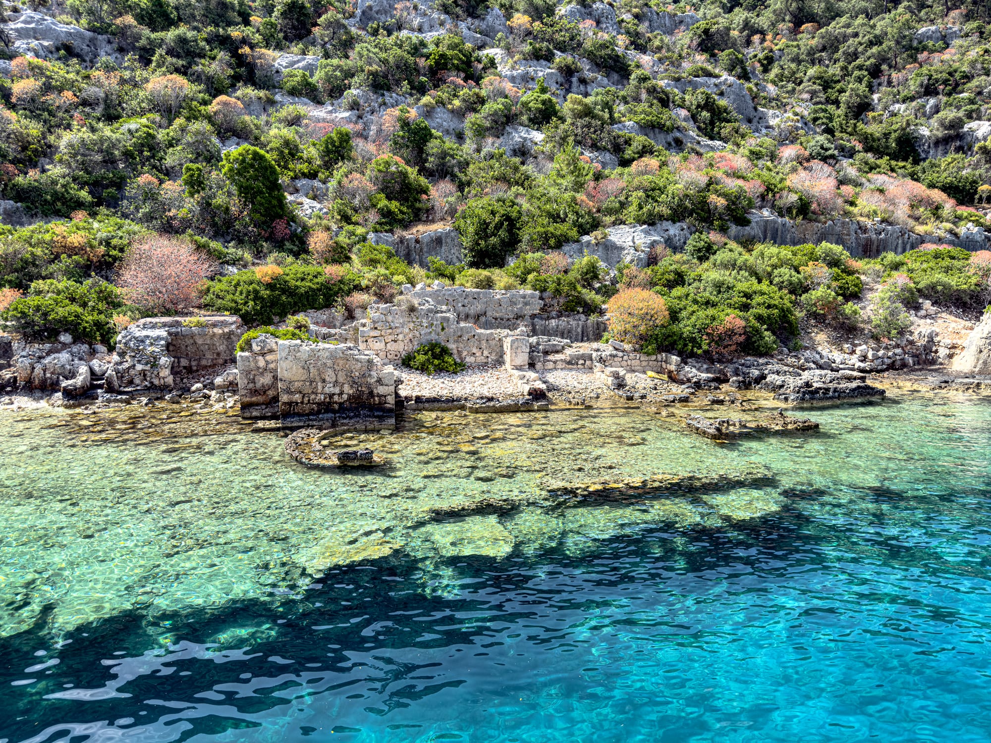 Partially submerged ruins of the ancient Lycian city of Kekova, with stone walls and foundations visible beneath clear blue water