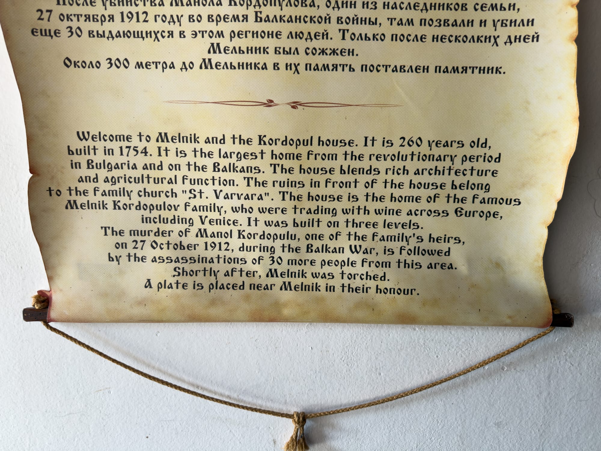 Informational plaque about the Kordopulov House in Melnik, Bulgaria, describing its history since 1754, its role as the largest Revival-era home in the Balkans, its use in wine trading across Europe, and the tragic events during the Balkan War in 1912