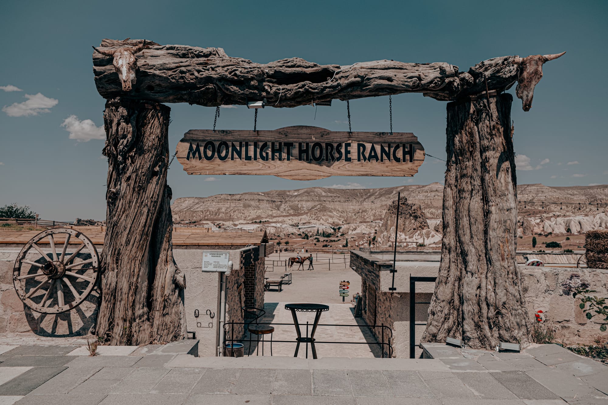 Entrance gate of Moonlight Horse Ranch in Cappadocia, featuring rustic wooden beams, carved signage, and panoramic mountain views