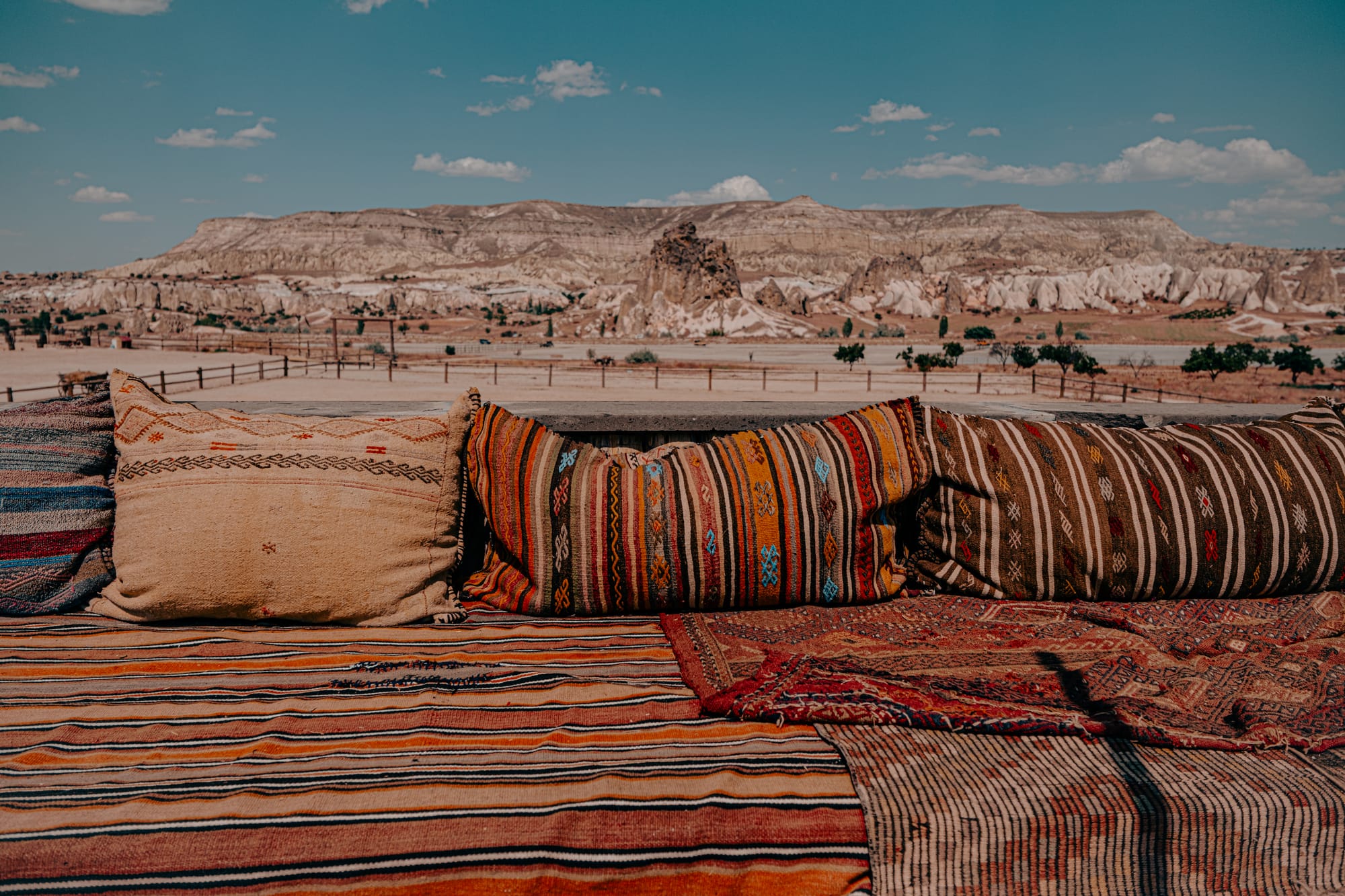 Colorful patterned cushions and rugs on a terrace at Moonlight Ranch, Cappadocia, with panoramic mountain views