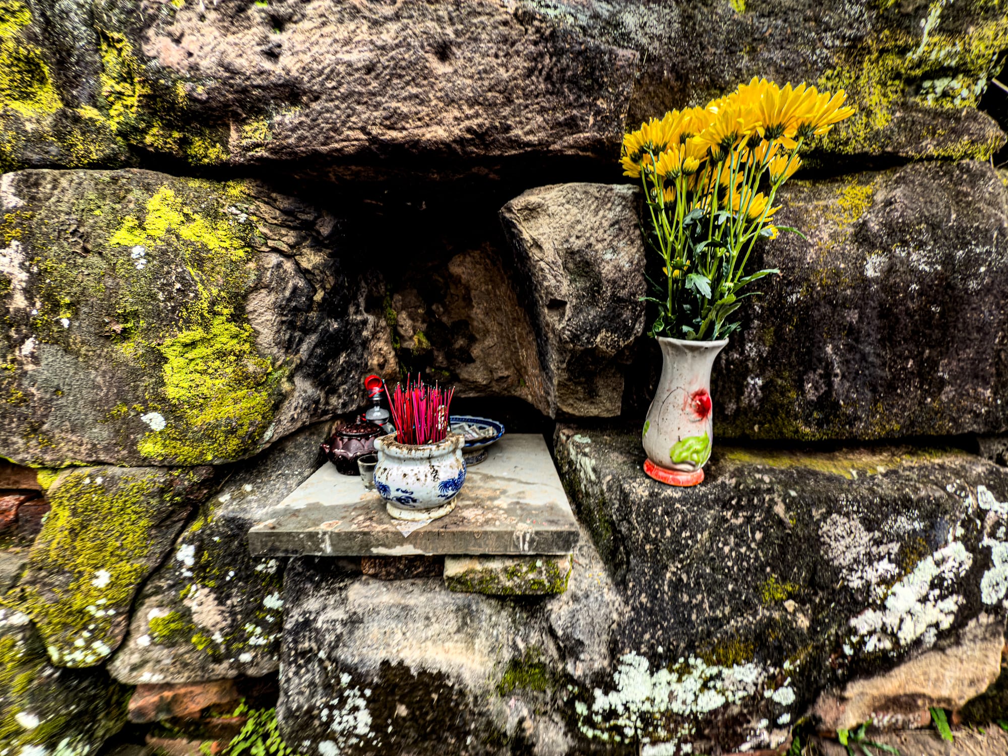 Incense sticks and yellow flowers placed as offerings at Mỹ Sơn Sanctuary Cham temple ruins in Vietnam