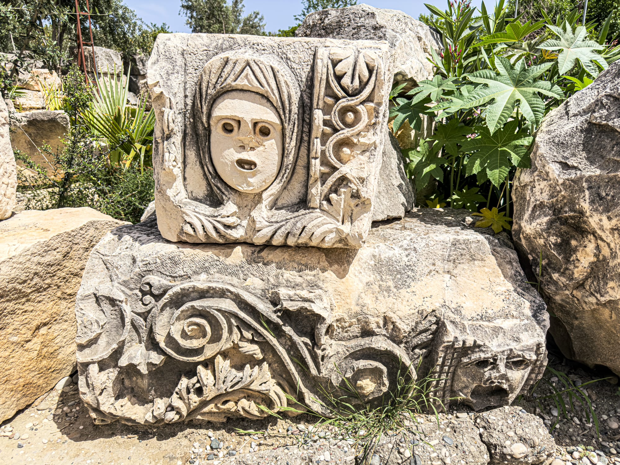 Ancient Roman relief from Myra in Demre, Turkey, showing carved theater mask and decorative vine motifs amidst ruins
