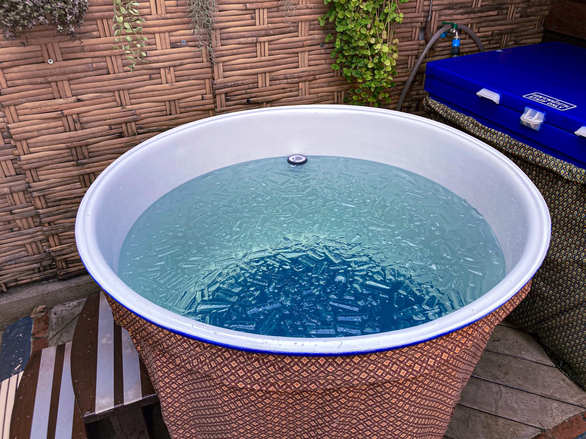 Round ice bath tub at Old City Spa in Chiang Mai filled with water and floating ice, set against a bamboo wall with plants hanging above