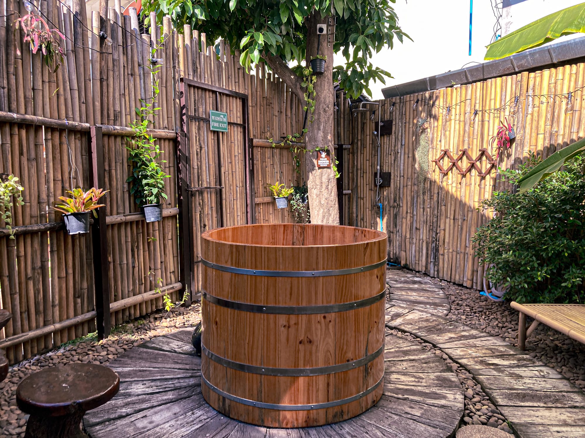 Wooden barrel-style ice bath at Old City Spa in Chiang Mai, set in a bamboo-fenced courtyard with a stone pathway, plants, and shaded seating