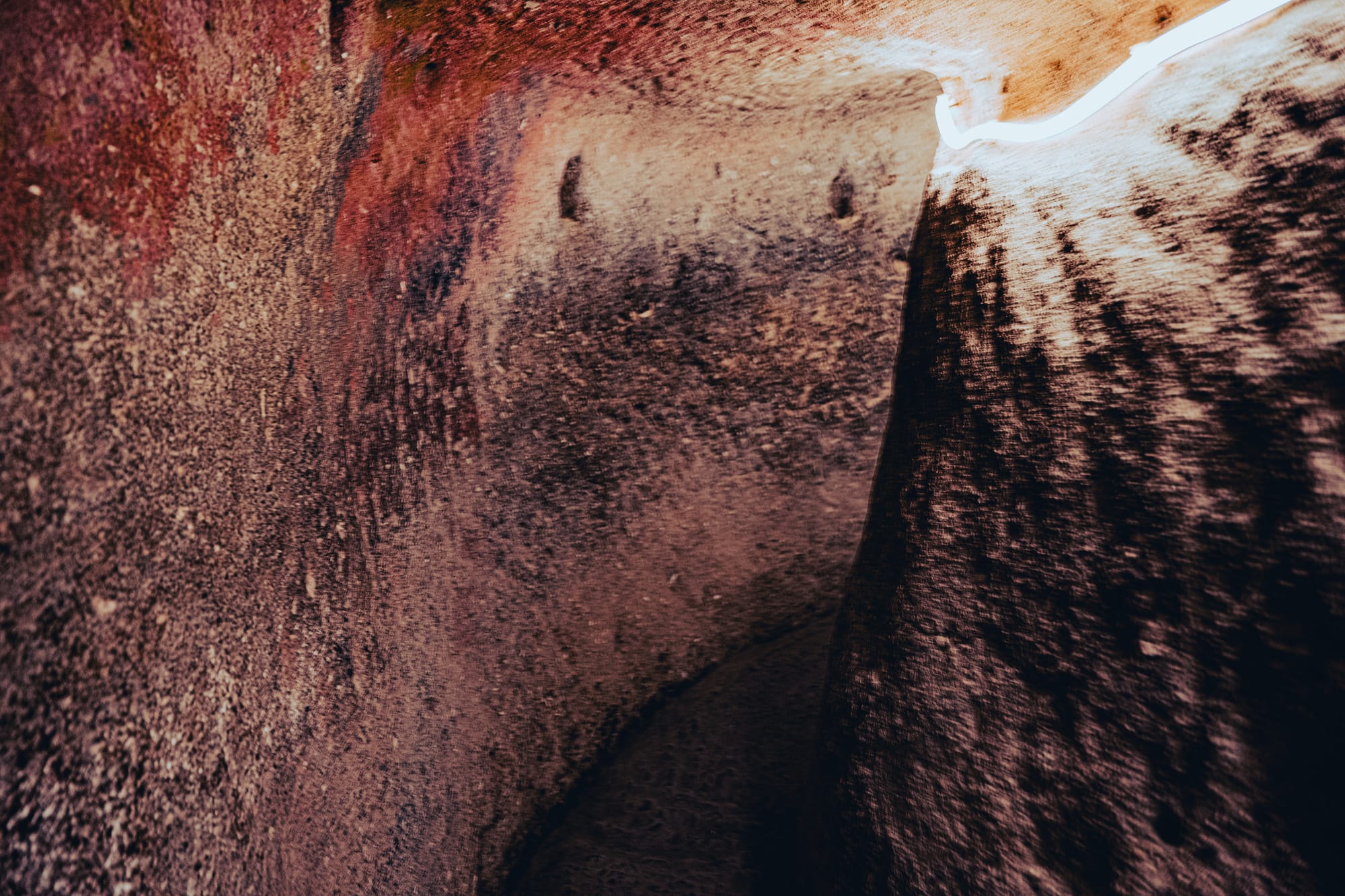 Narrow passageway with textured stone walls inside Özkonak Underground City in Cappadocia