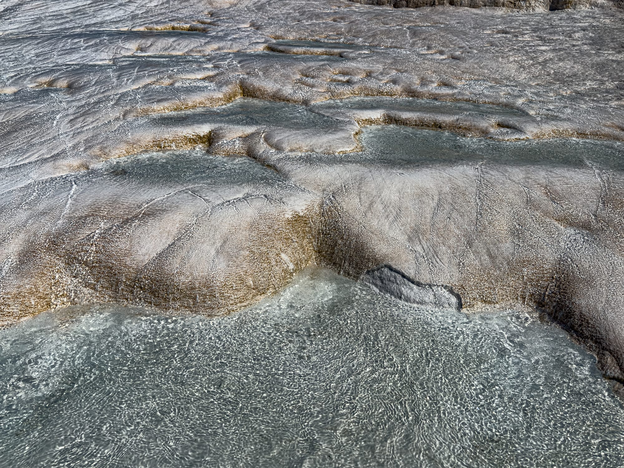 Close-up of Pamukkale’s textured travertine ledges with mineral-rich water glistening in soft light