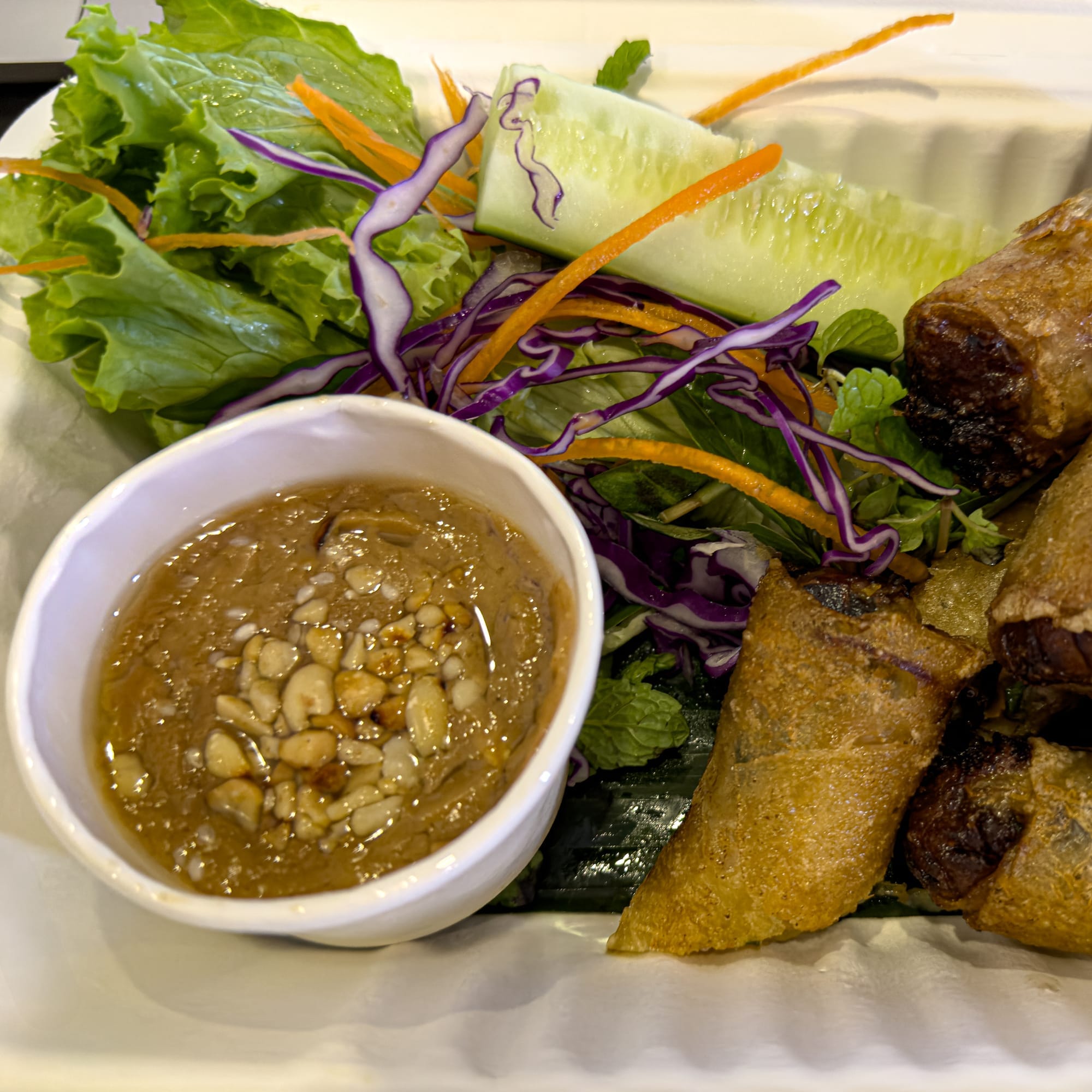 Vegan fried spring rolls from Peanuts in Hội An served with peanut dipping sauce, fresh lettuce, cucumber, shredded carrot, purple cabbage, and mint