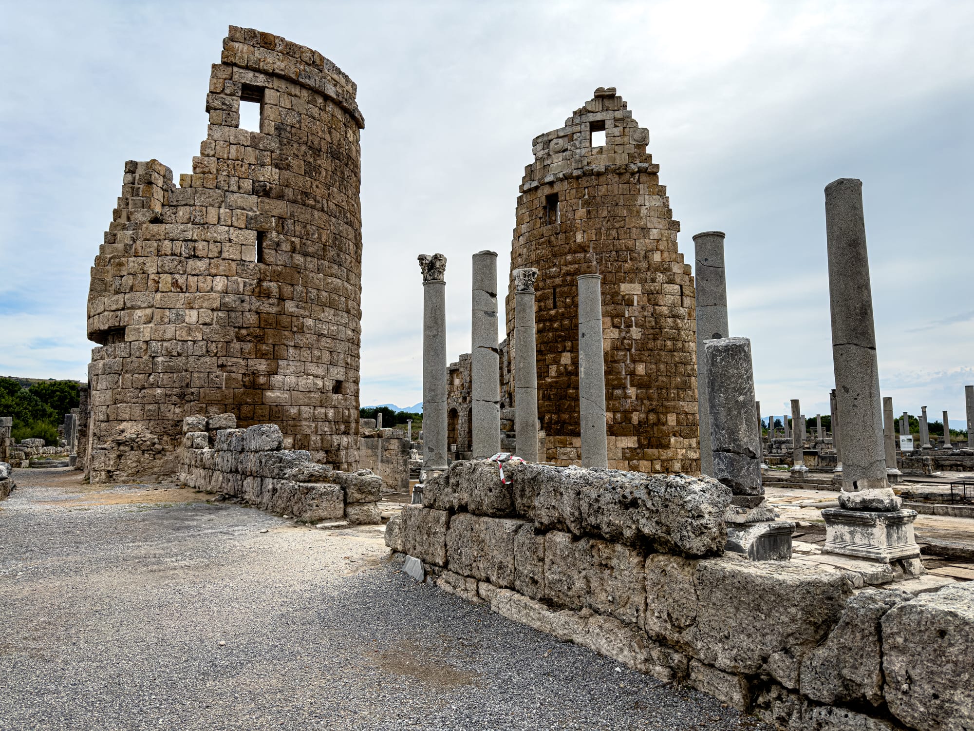 Twin round towers and stone columns of the Hellenistic Gate at Perge under a cloudy sky near Antalya, Turkey