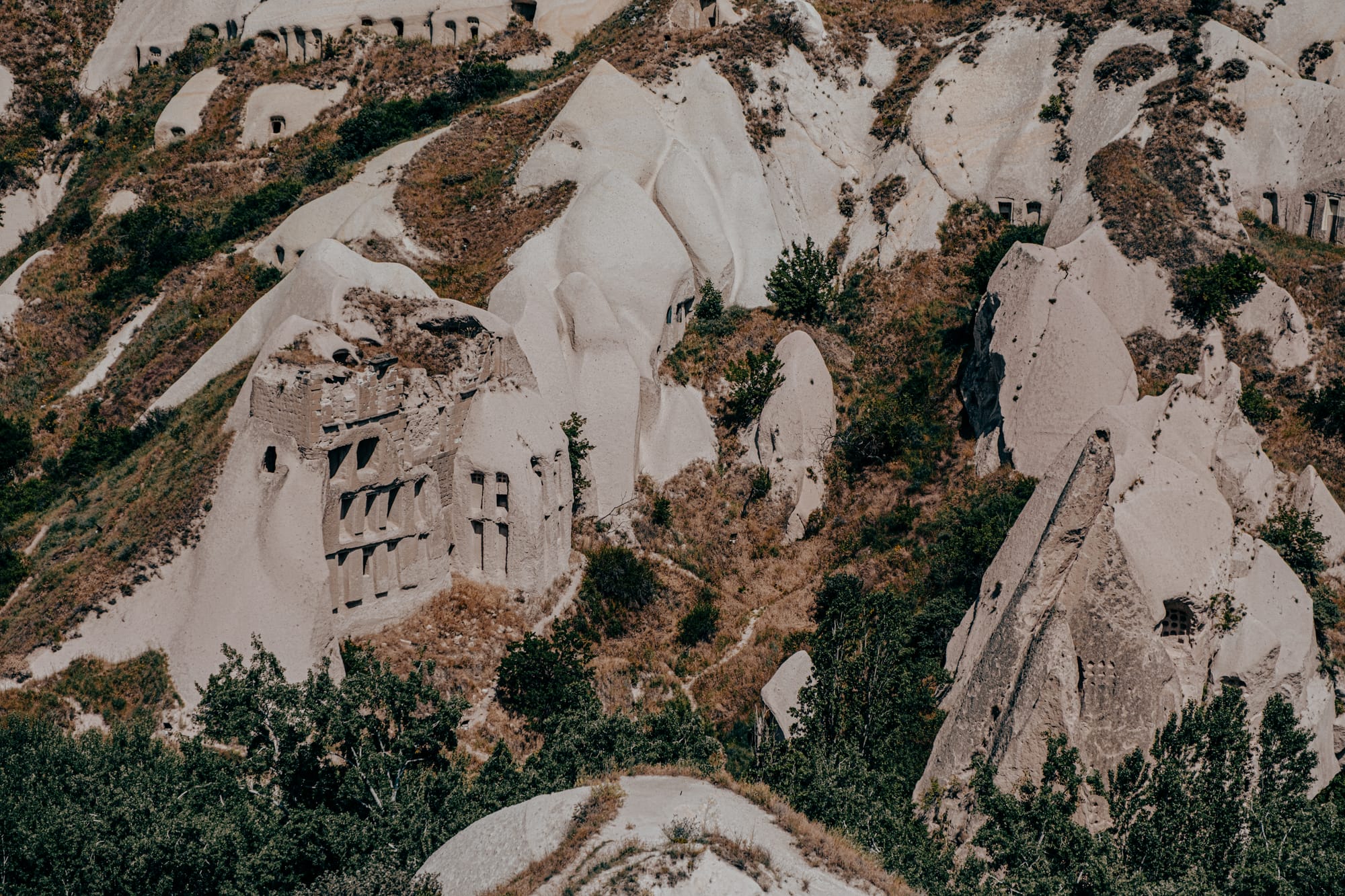 Ancient rock carved dwellings in Pigeon Valley surrounded by rugged slopes and natural rock formations
