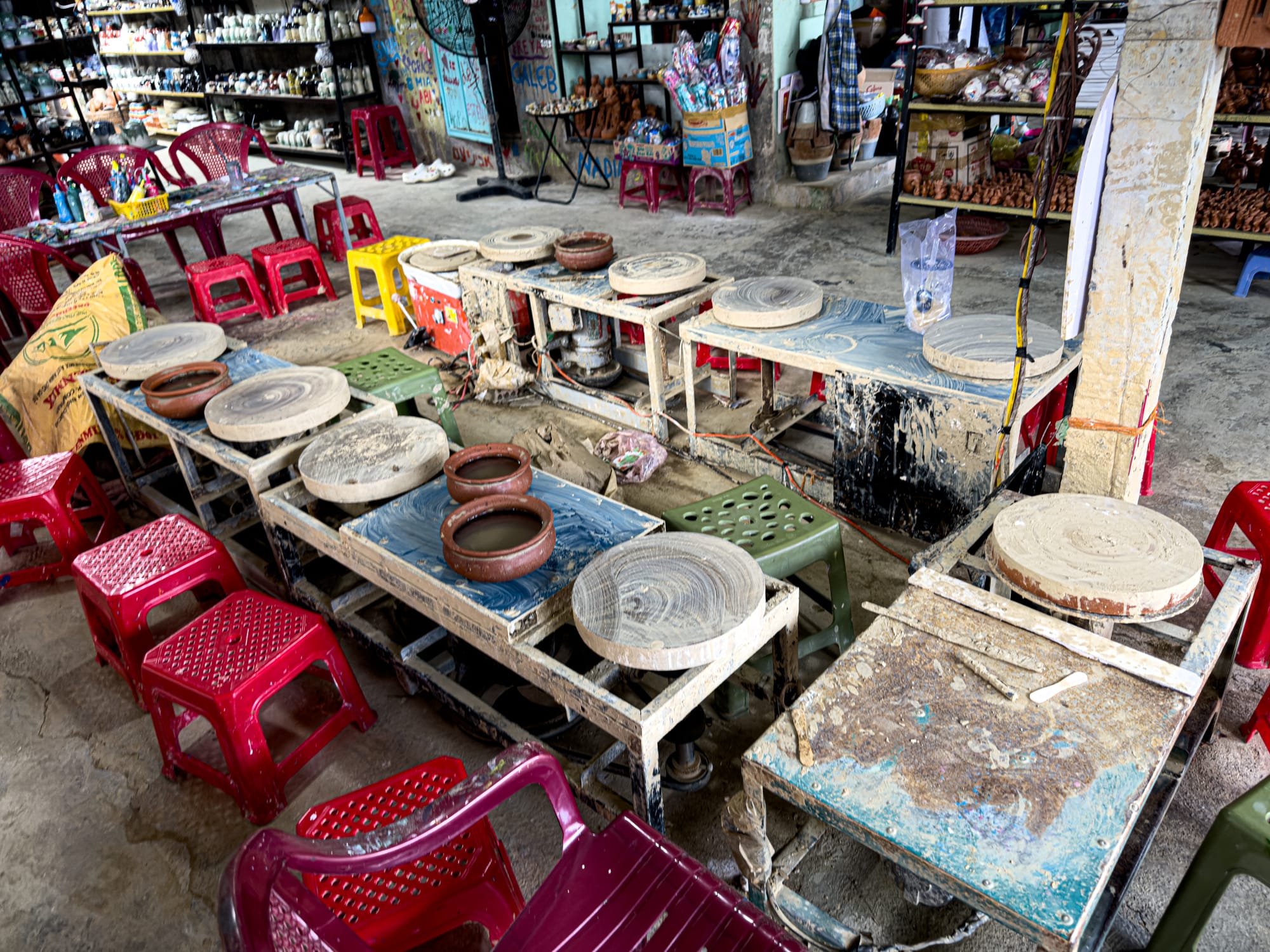 Row of pottery wheels and stools in a workshop at Thanh Hà Pottery Village Hội An, offering hands-on experiences for visitors and digital nomads interested in traditional ceramics