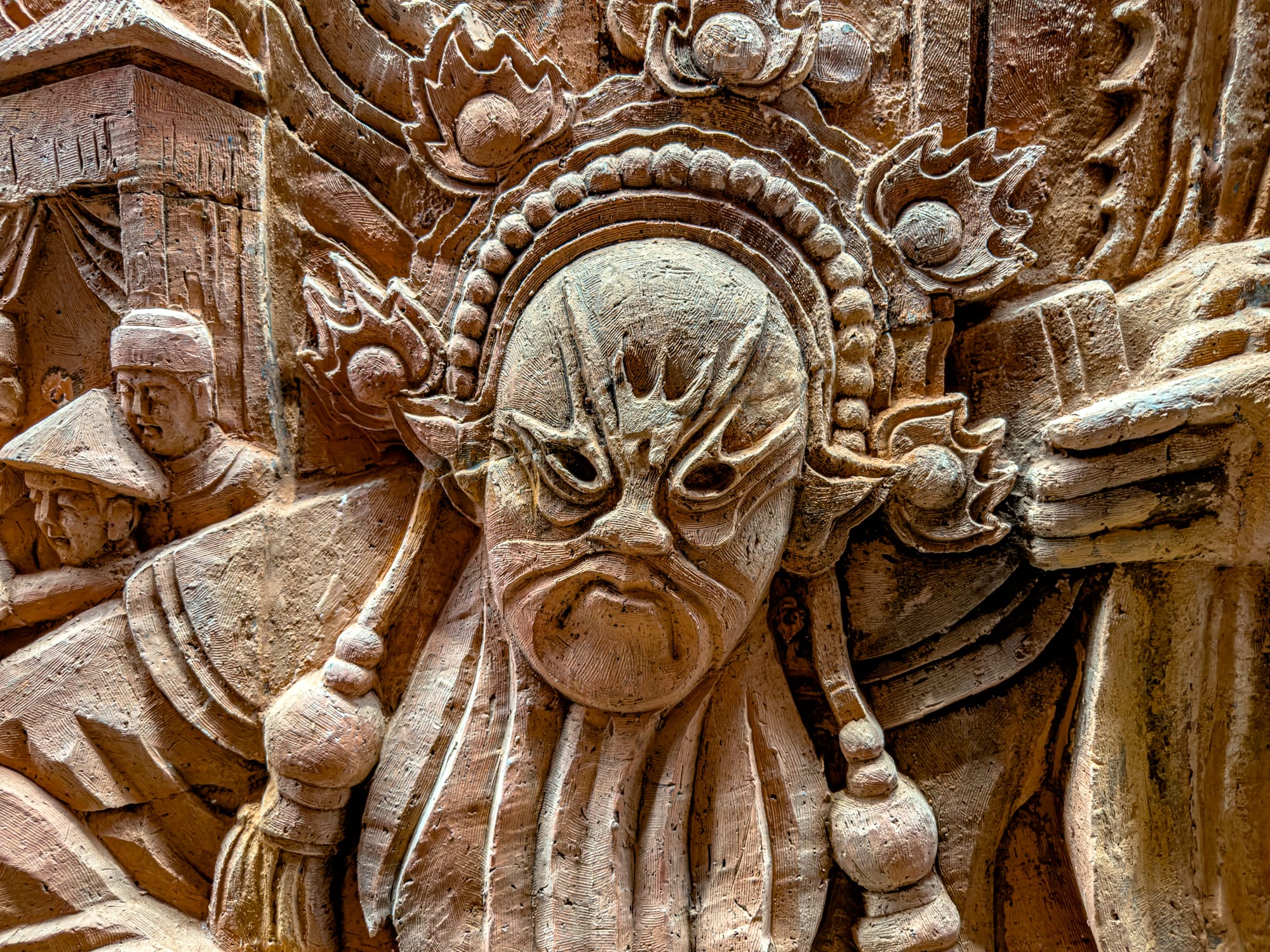 Close-up of a terracotta bas-relief mask sculpture at Thanh Hà Pottery Village Hội An, showcasing traditional Vietnamese artistry in clay
