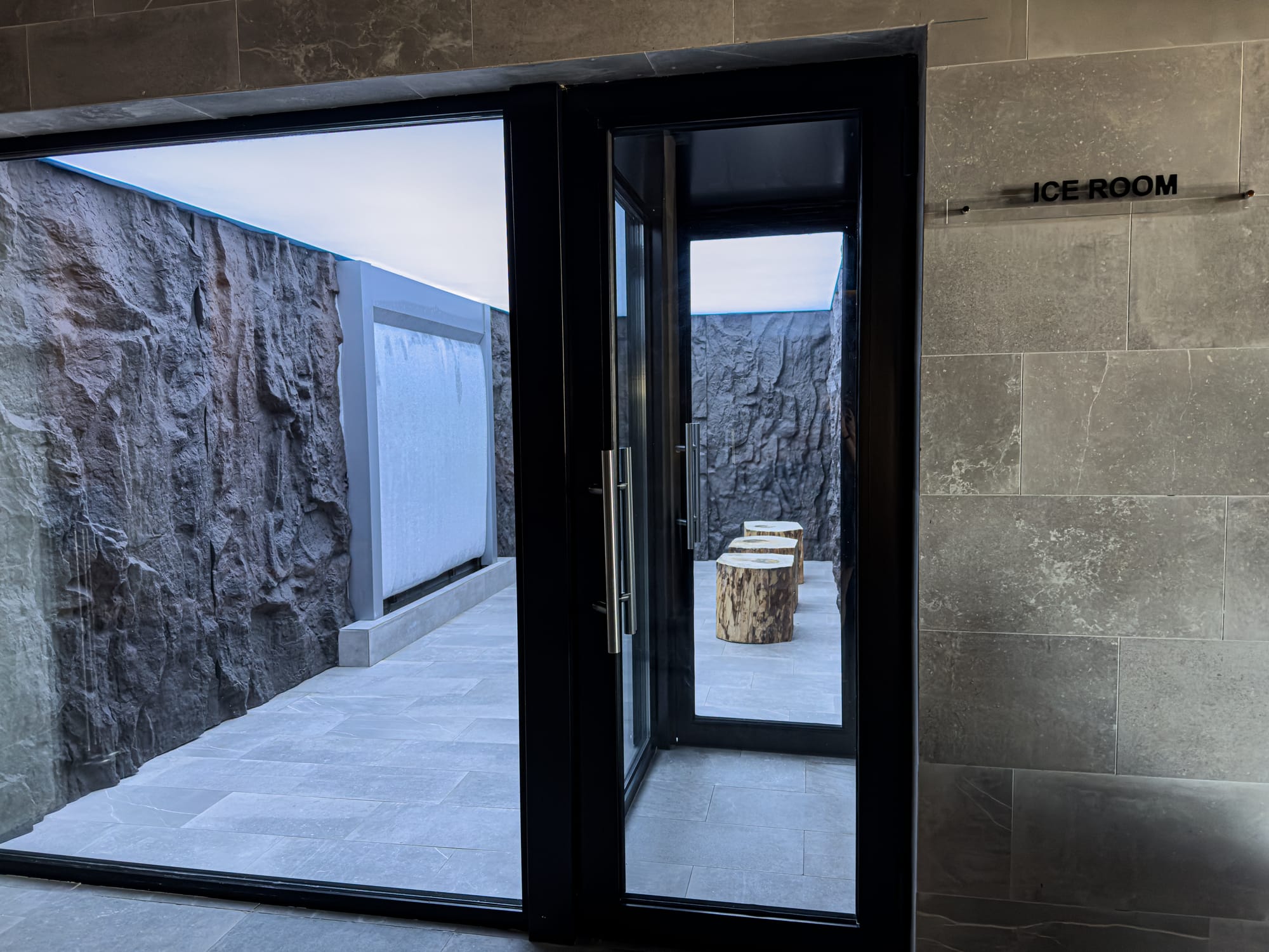 Entrance to the Ice Room at Pulse Thermal Spa in Banya, Bulgaria, showing stone walls, frosted glass, and wooden stools inside