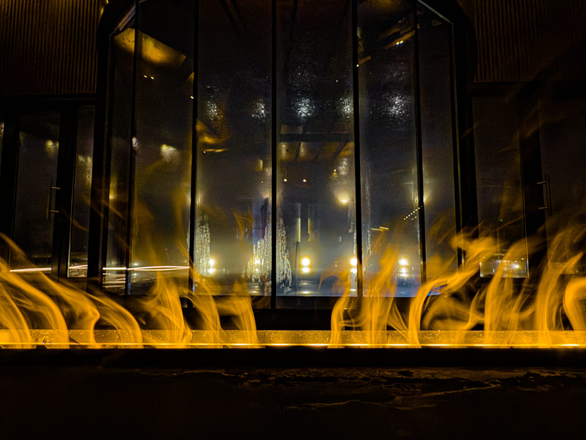 Close-up view of flames inside Pulse Thermal Spa in Banya, Bulgaria, with reflections of lights and windows in the background