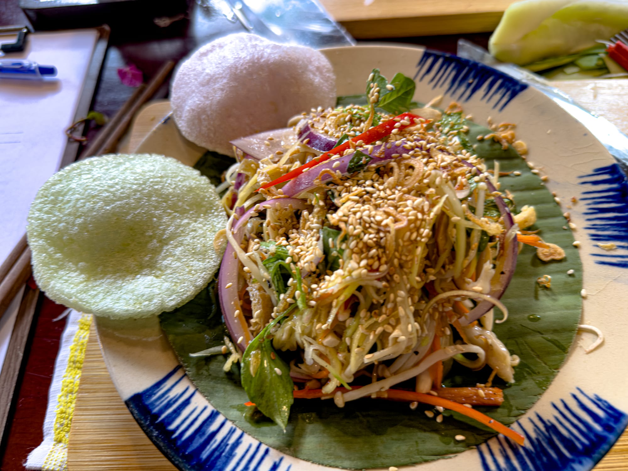 Banana blossom salad with herbs onions sesame seeds and rice crackers at Rau Ơi Eatery vegan cooking class in Hội An, Vietnam