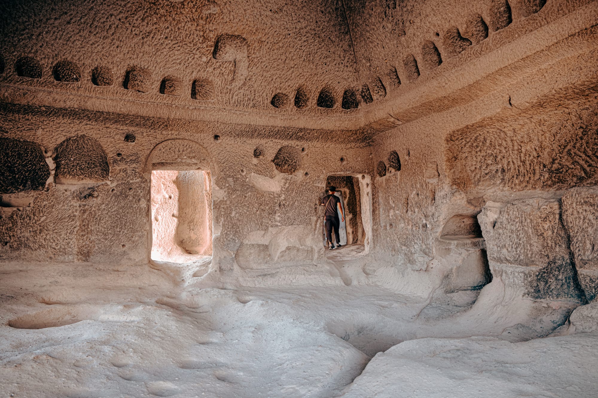 Interior of Selime Monastery showing a large rock-carved chamber with arched doorways and intricate niches