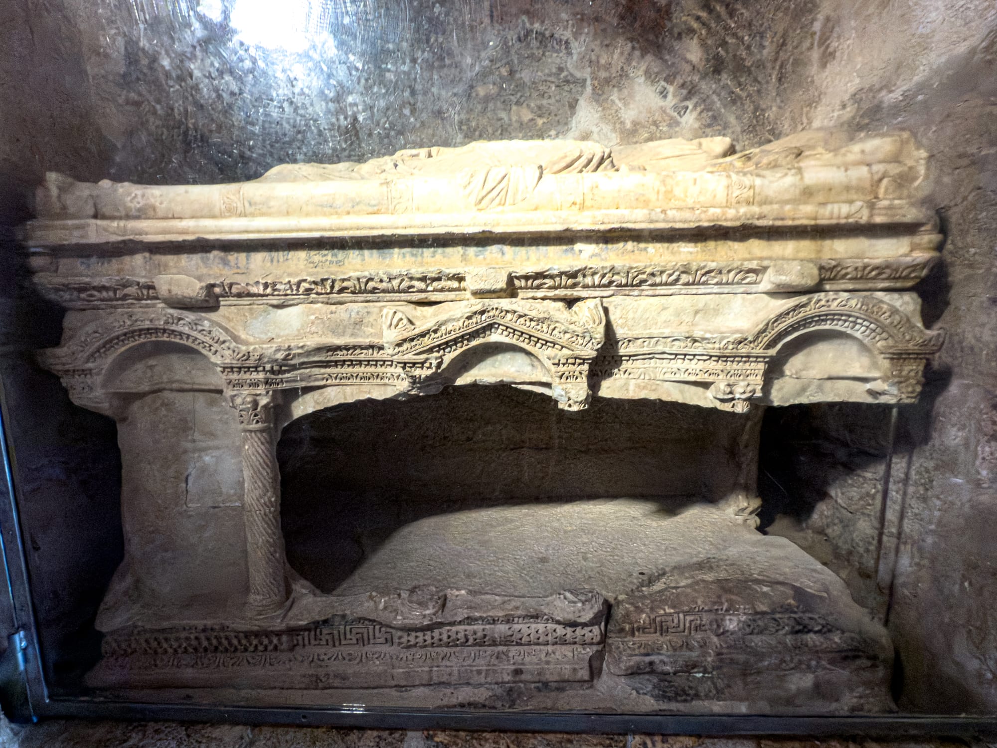 Sarcophagus of Saint Nicholas inside his church in Demre, Turkey, adorned with carved arches and columns, marking his original burial site in Byzantine architecture