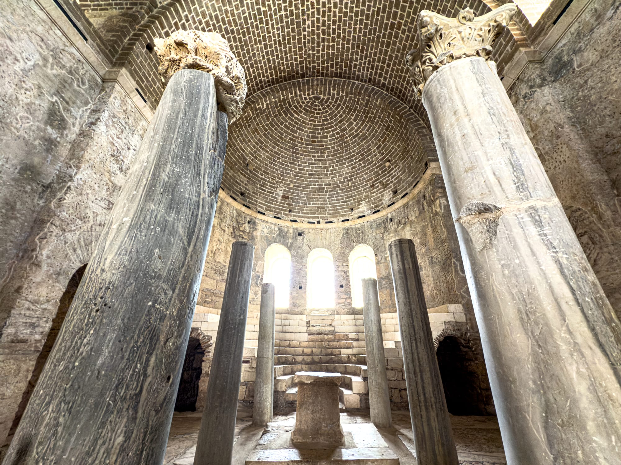 Interior view of Saint Nicholas Church altar in Demre, Turkey, with domed ceiling and marble columns forming a semicircle around a raised stone platform