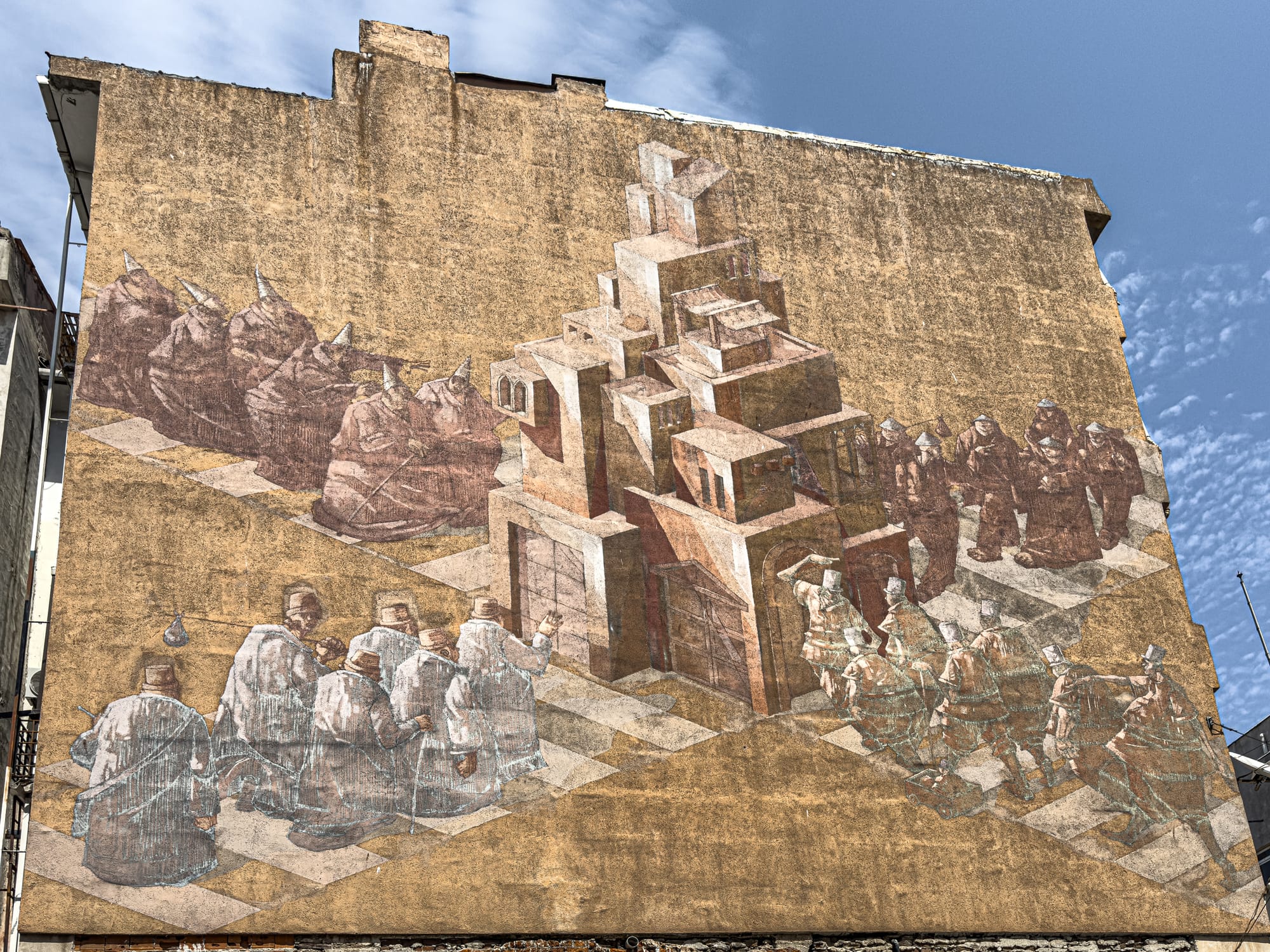 Mural by Sepe and Chazme on a tan building wall, showing layered architectural structures surrounded by stylized, semi-transparent figures in traditional garb, arranged in diagonal formation across a warped checkerboard floor