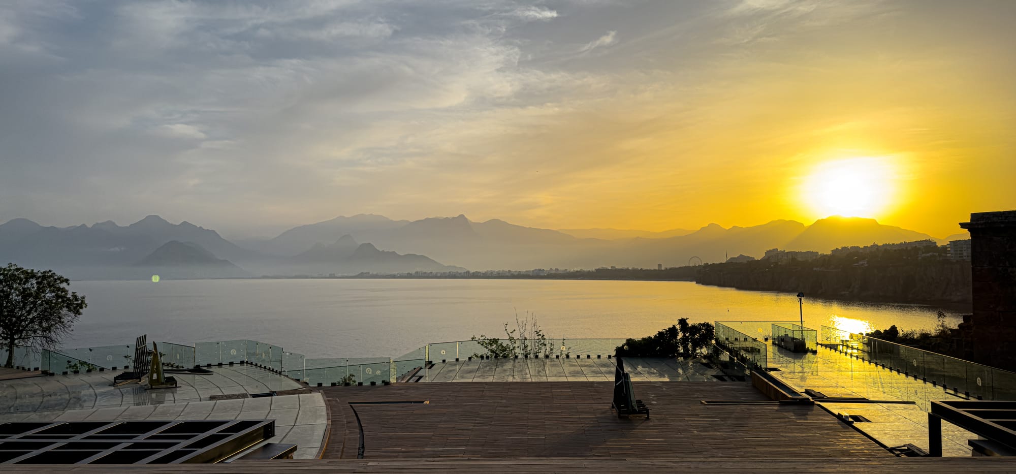Golden sunset over the Gulf of Antalya viewed from Karaalioğlu Park, with the sea, mountains, and cliffs bathed in warm evening light