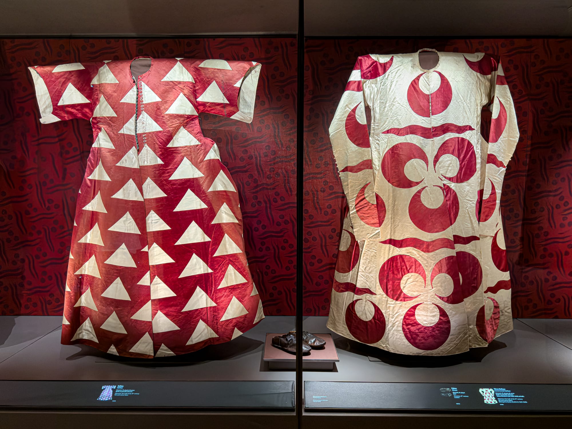 Two richly patterned Ottoman kaftans on display, adorned in bold red and white geometric designs