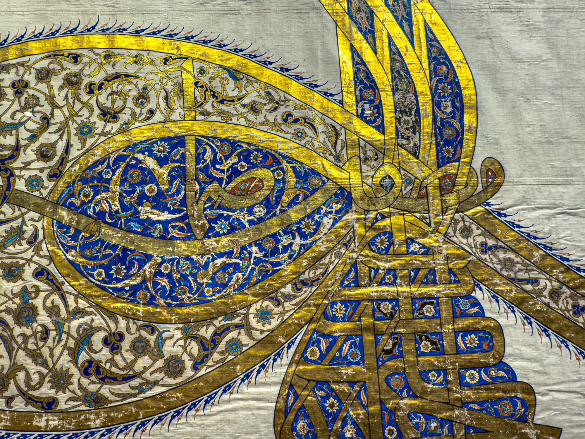 Close-up of an ornate Ottoman tughra in gold, blue, and black calligraphy on silk