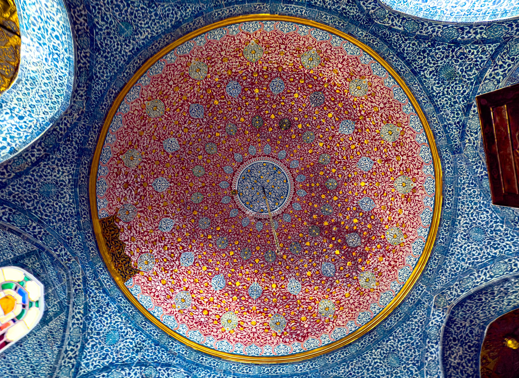 Ornate Ottoman dome with intricate red, blue, and gold tile patterns and geometric floral motifs