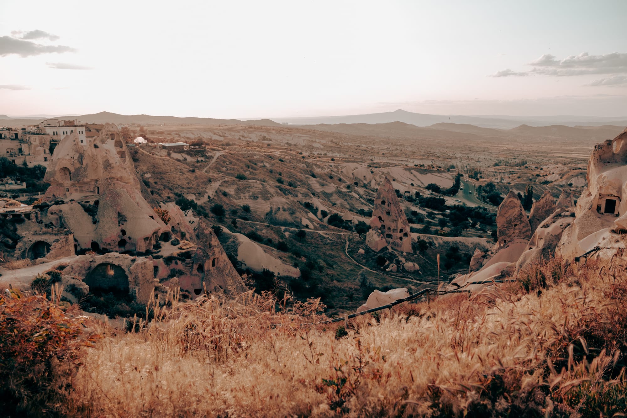 Uçhisar Castle Cappadocia sunset view of surrounding valleys, carved rock formations, and golden fields from ridge viewpoint