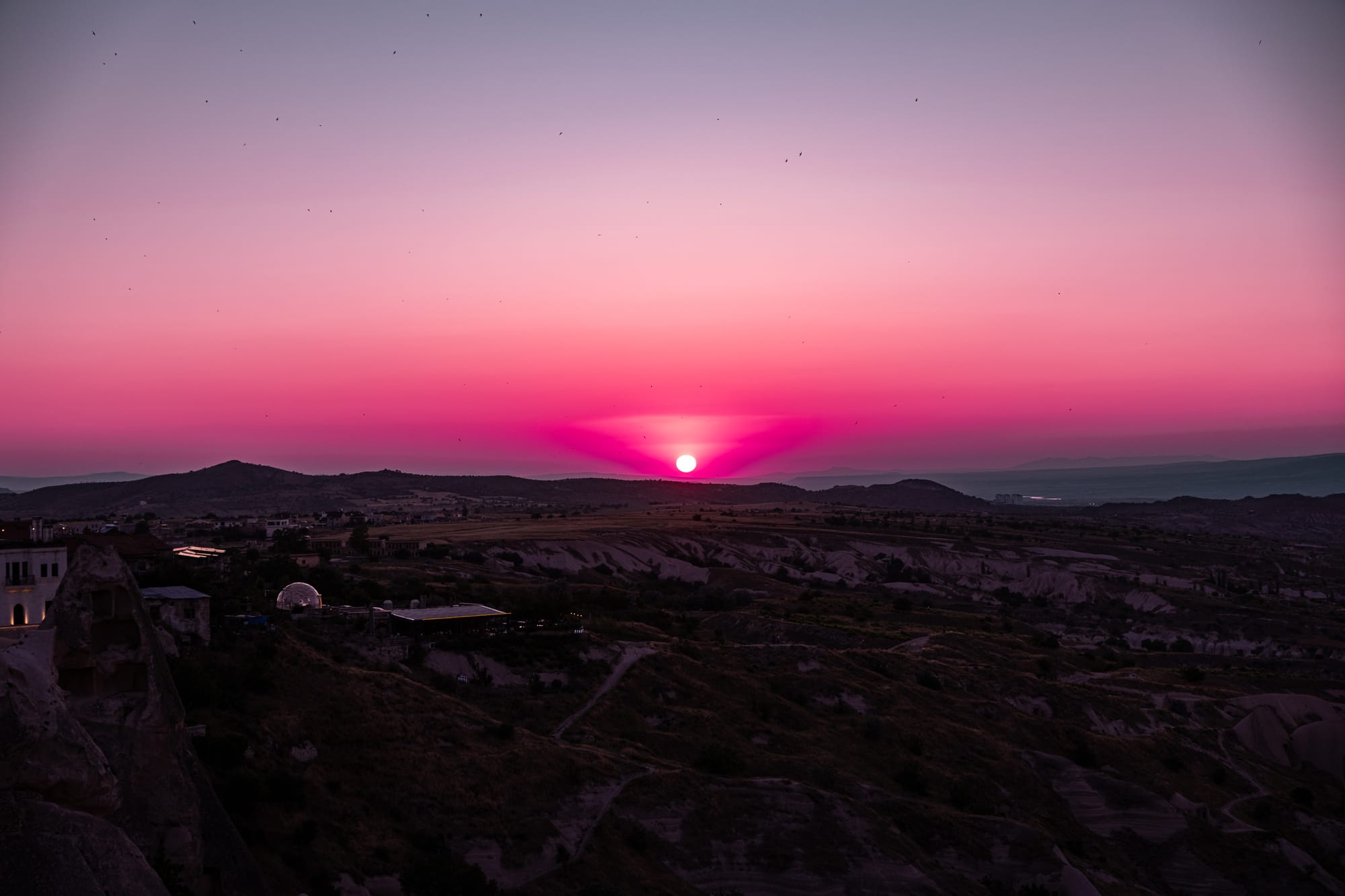 Uçhisar Castle Cappadocia sunset view with vivid pink and purple sky above valleys and distant mountains