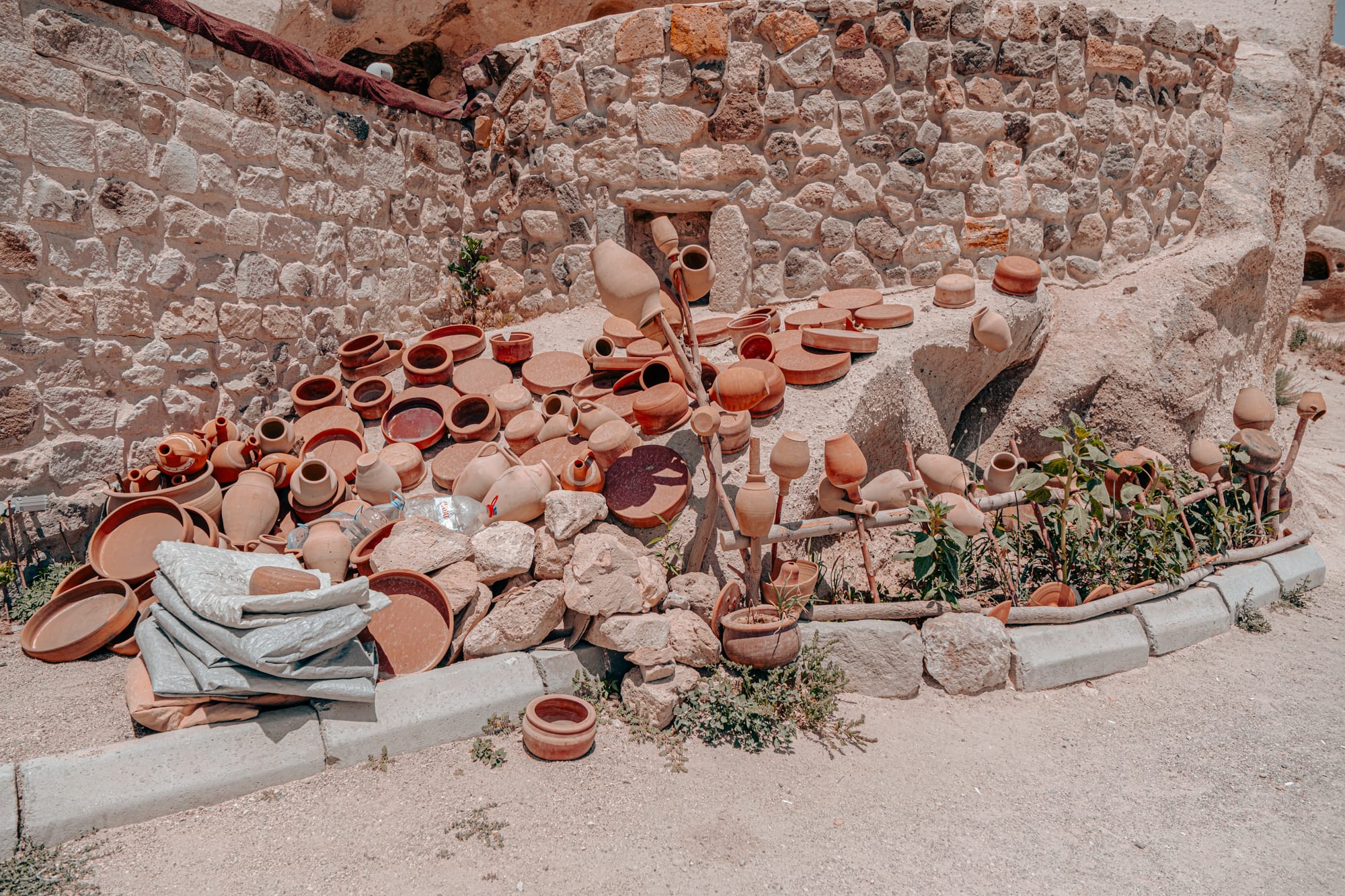 Uçhisar Castle Cappadocia display of traditional clay pots and terracotta vessels near stone walls