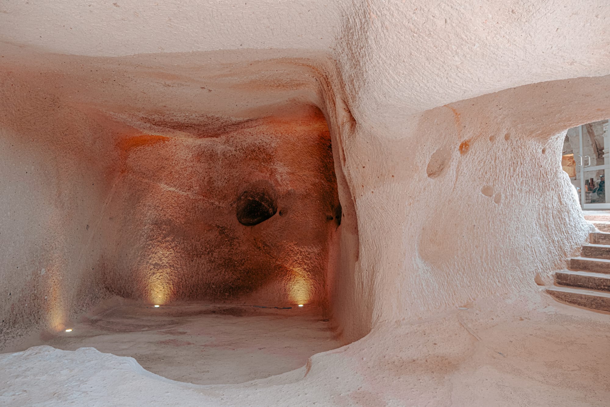 Uçhisar Castle interior chamber with smooth rock walls carved from volcanic stone and lit floor spots
