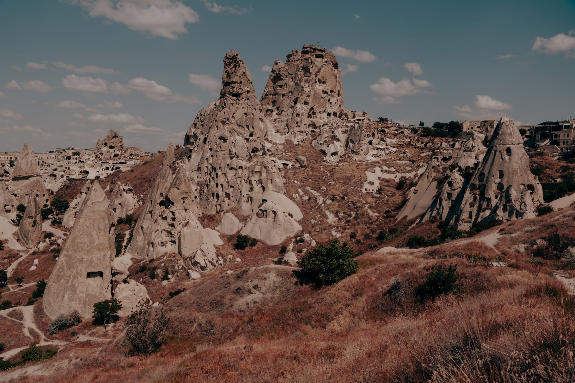 Uçhisar Castle Cappadocia wide view showing rock citadel with carved dwellings and surrounding walking trails in dry valleys
