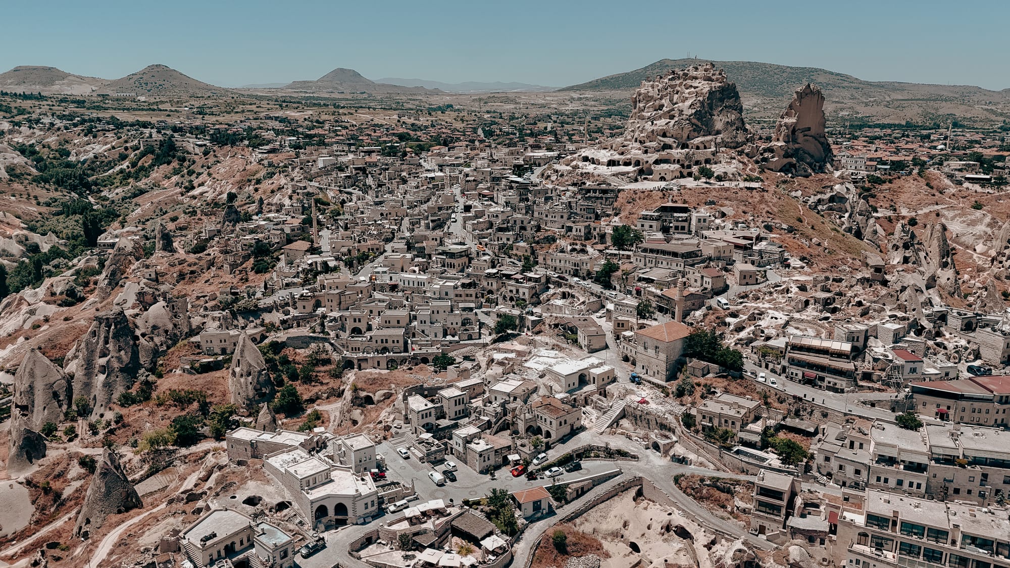 Uçhisar Castle Cappadocia aerial view showing stone houses, rock formations, and the castle towering over the town