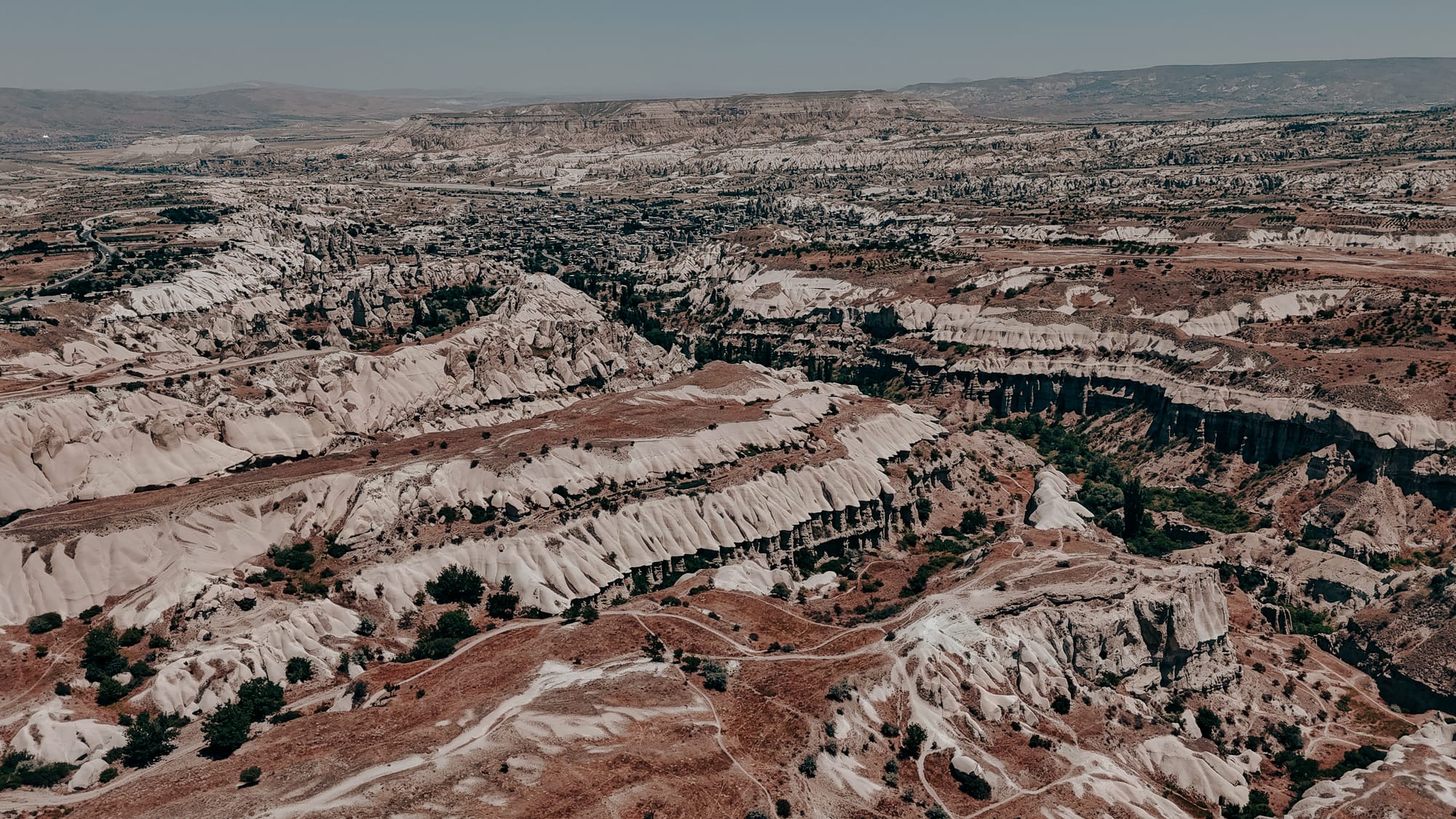 Uçhisar Castle Cappadocia aerial view of surrounding valleys with eroded ridges, walking paths, and sweeping landscapes