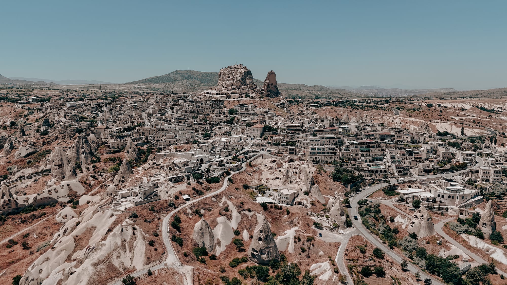 Uçhisar Castle Cappadocia panoramic aerial view showing the castle, surrounding village, and nearby valley trails
