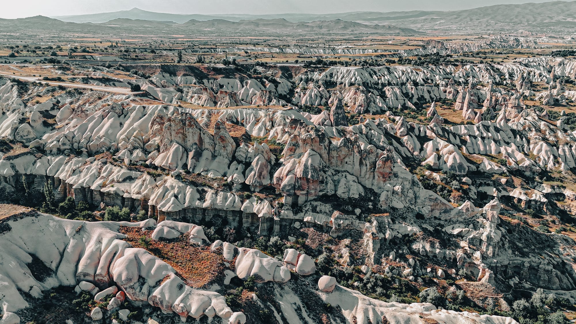 Uçhisar Castle Cappadocia aerial valley view showing eroded ridges, rock formations, and sweeping landscapes surrounding the castle