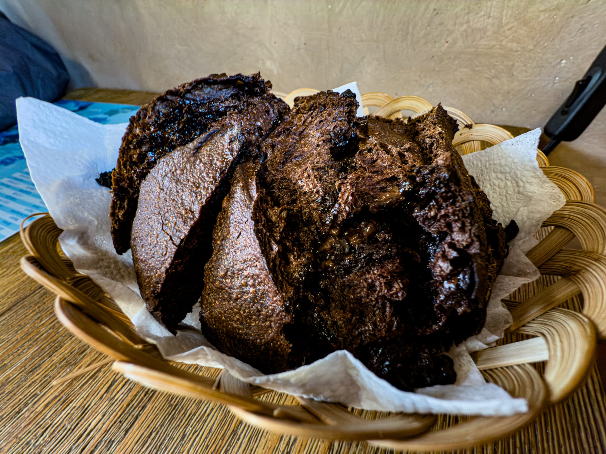 Basket of freshly baked vegan cacao loaf from The French Guy microbakery in Bansko, with dark, rich slices of bread resting on paper