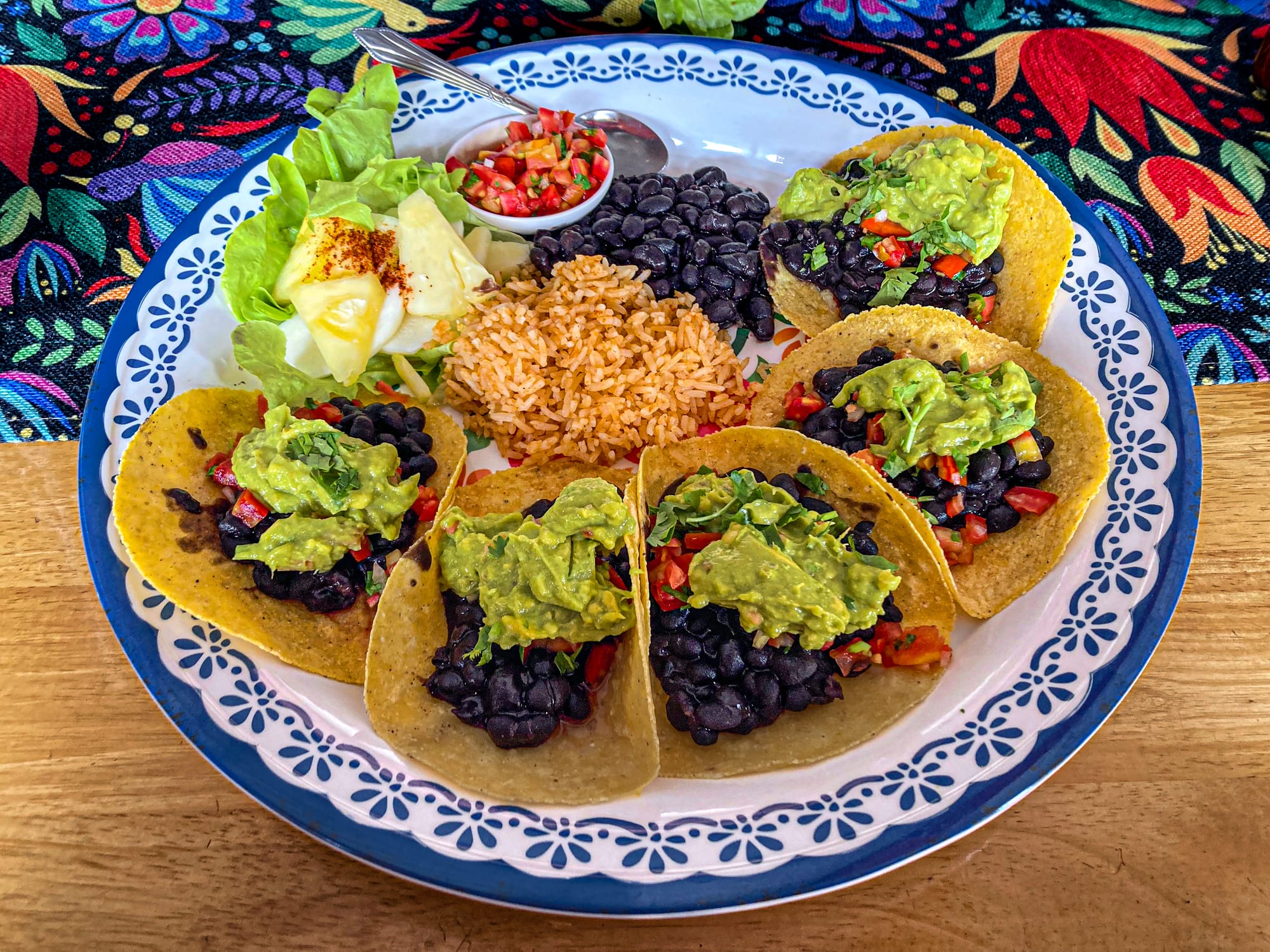 Plate of five tacos filled with black beans, diced red peppers, and guacamole, served with Mexican rice, black beans, pineapple sprinkled with chili powder, and a small bowl of salsa at Salsa Kitchen in Chiang Mai