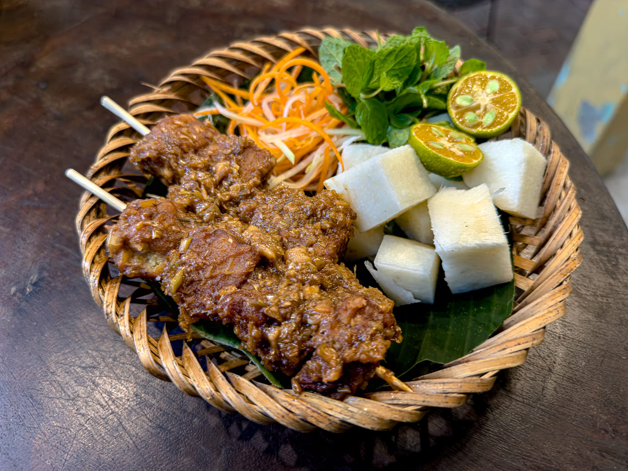 Chickpea tempeh skewers at Chickpea Eatery in Hội An served with fresh herbs, pickled carrot and papaya, lime, and cubes of jicama on the side