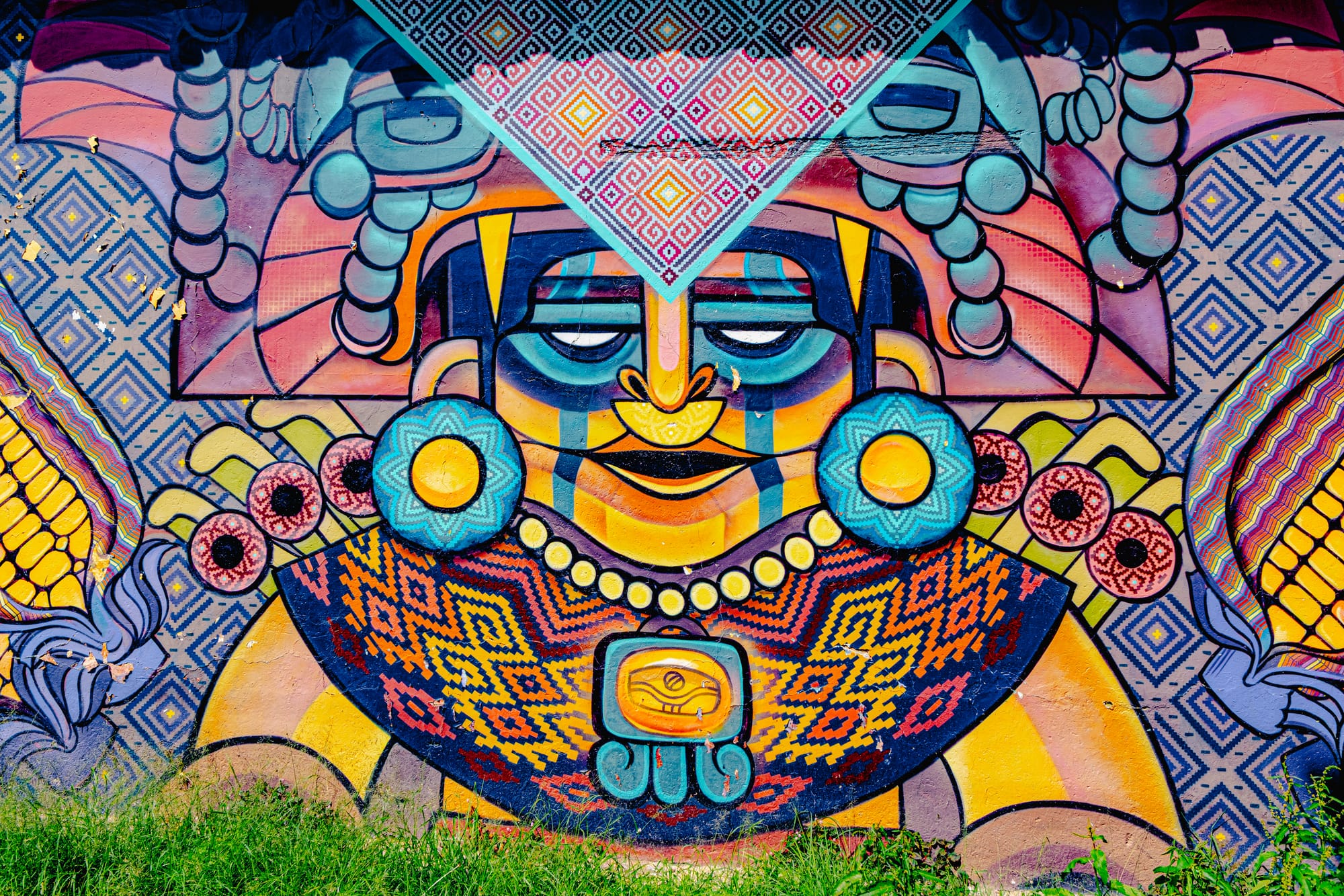 Close-up of a colorful mural in El Cerrillo, San Cristóbal de las Casas, depicting a stylized Indigenous figure adorned with geometric patterns, maize motifs, and woven textile designs, blending traditional Mayan symbolism with modern Mexican street art