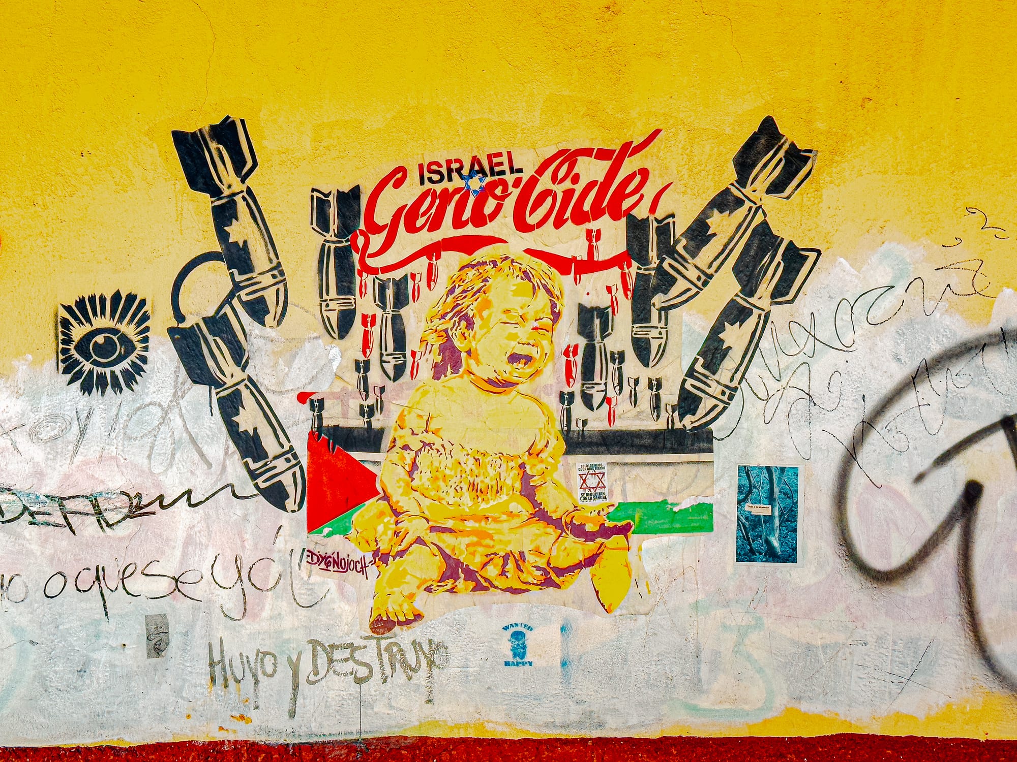 A politically charged mural in El Cerrillo, San Cristóbal de las Casas, showing a crying child surrounded by falling bombs and the word “Genocide” written above “Israel,” painted on a yellow wall as a statement of solidarity with Palestine and global resistance movements