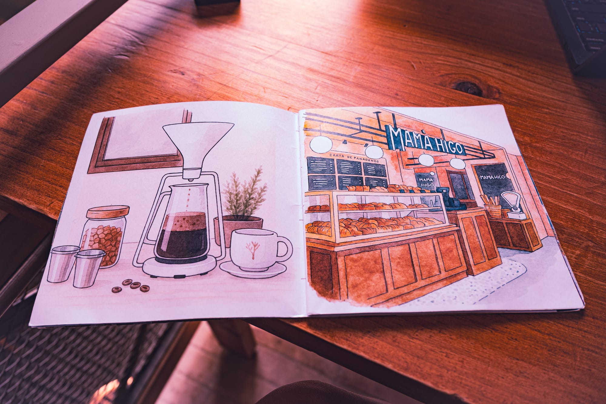 An illustrated booklet at Histórico Café in San Cristóbal de las Casas showing drawings of a pour-over coffee setup and the Mamá Higo bakery counter