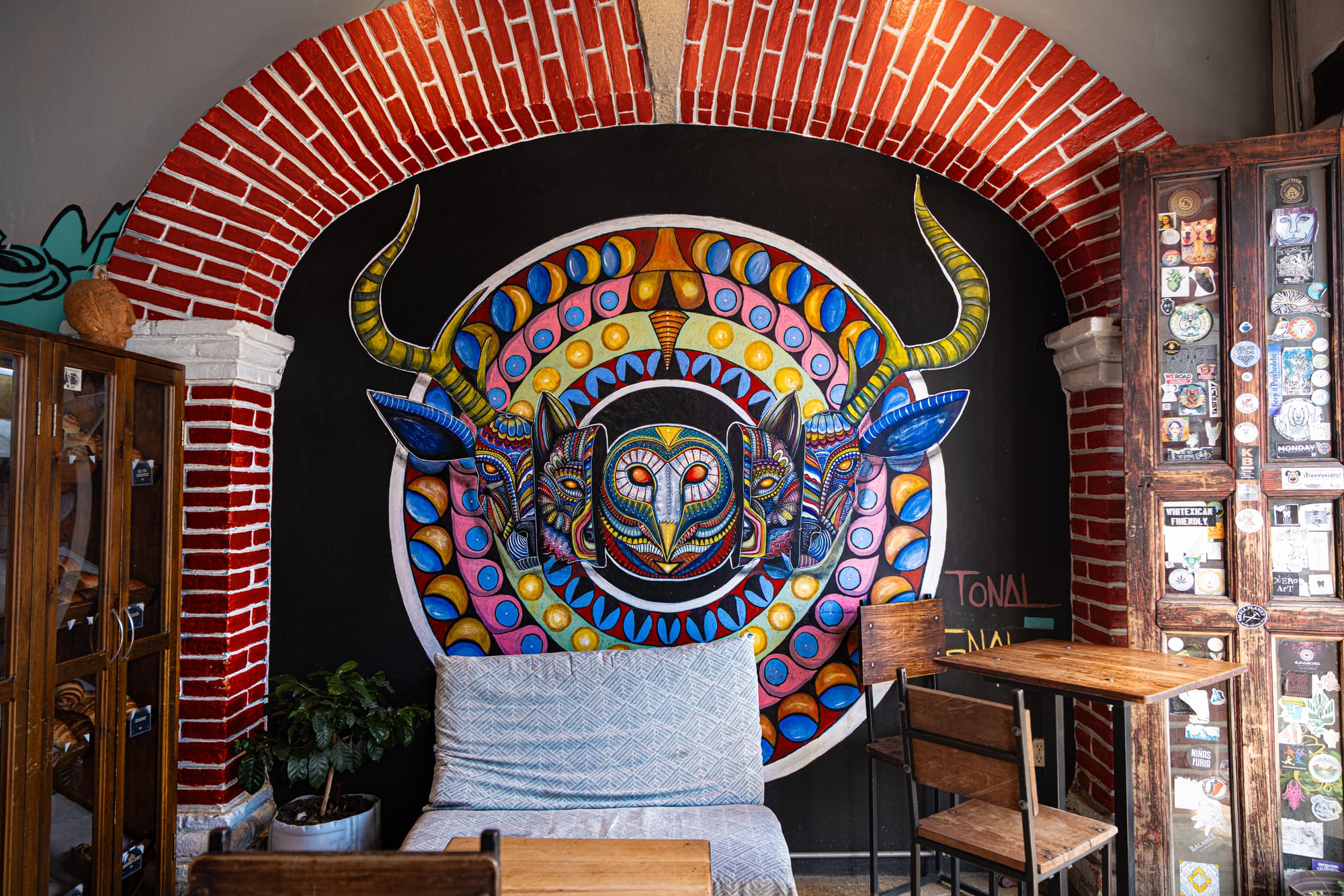 A colorful mural at Kukulpan café in San Cristóbal de las Casas, featuring a circular design with stylized animal faces and horns painted under a brick archway