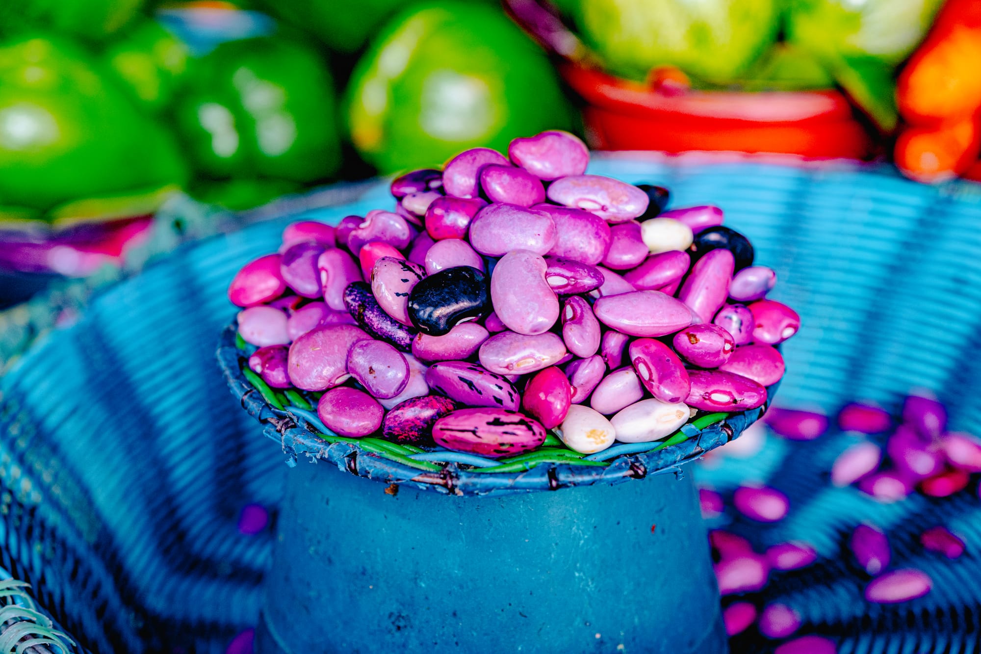Close-up of colorful pink, purple, and black beans in a woven blue basket at Santo Domingo Market in San Cristóbal de las Casas, Chiapas, highlighting local heirloom varieties