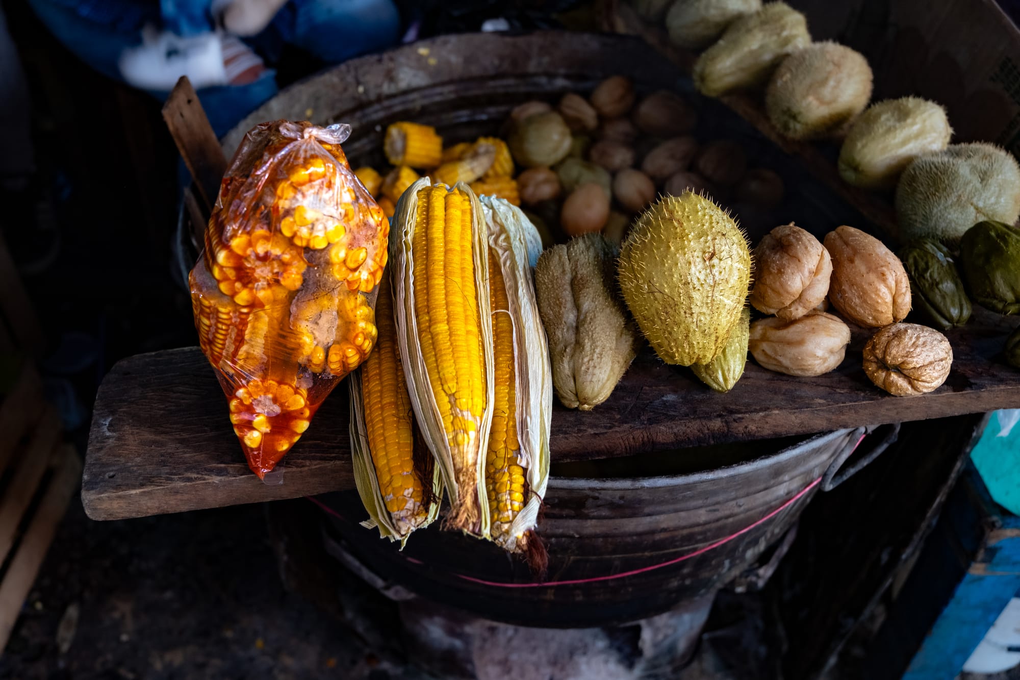 Close-up of boiled corn, chayote, and other local vegetables arranged on a wooden plank over a metal cooking pot at Santo Domingo Market in San Cristóbal de las Casas, Chiapas
