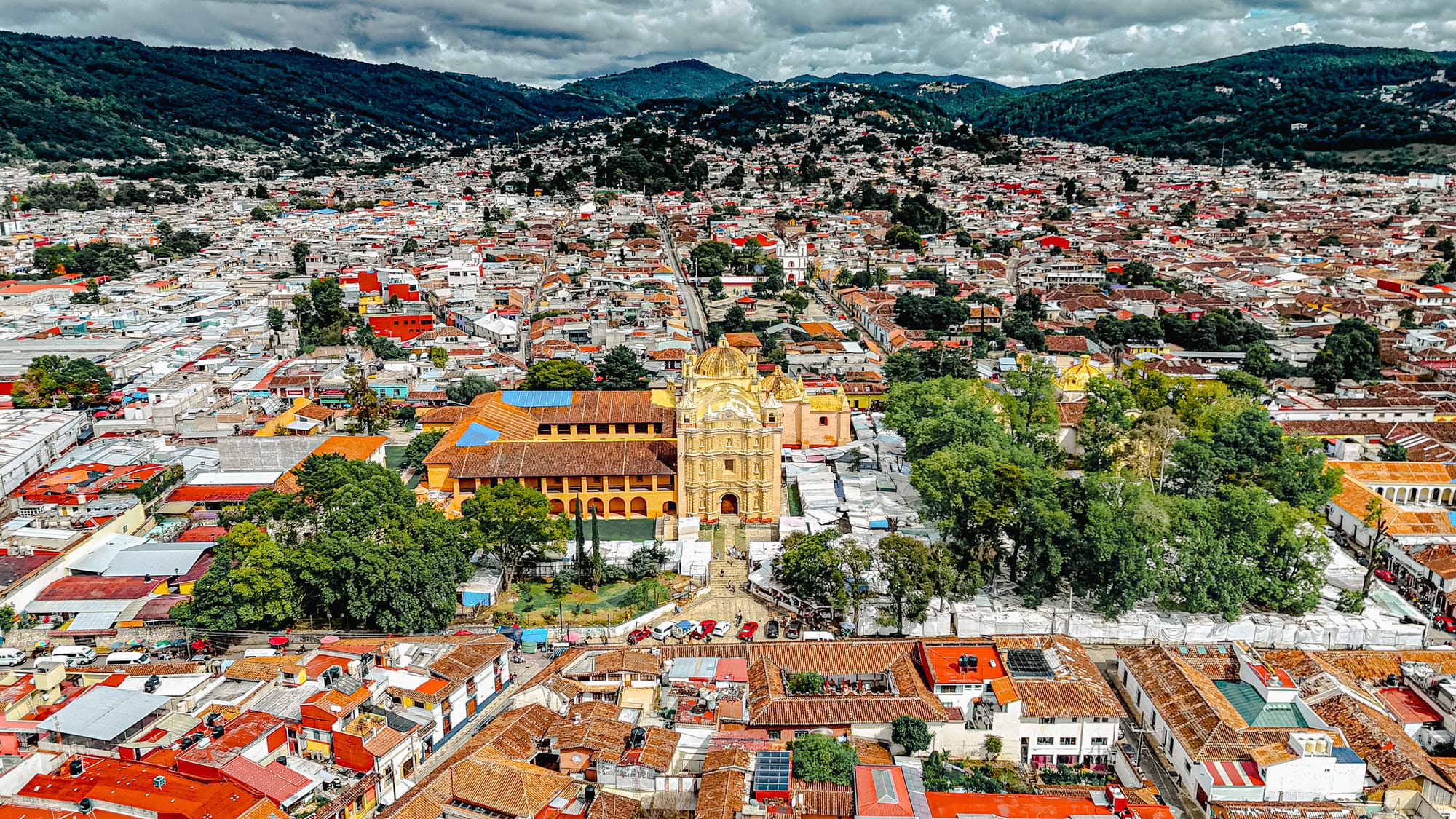 Aerial view of the Templo de Santo Domingo in San Cristóbal de las Casas, Chiapas, Mexico, surrounded by red rooftops and the mountains of the highlands, where the city’s food market takes place nearby