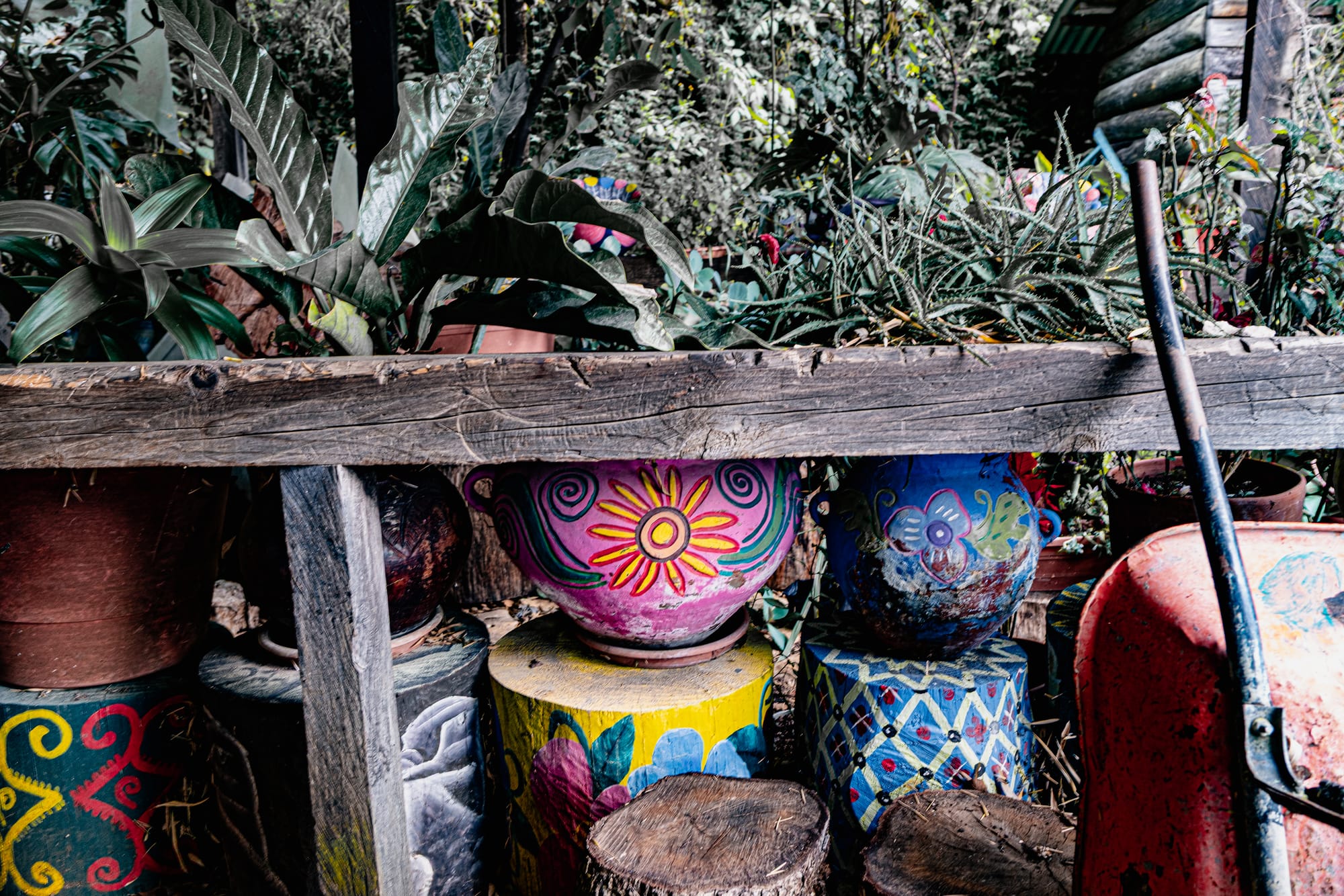 Colorful hand-painted flower pots and decorated wooden stumps in an outdoor garden area
