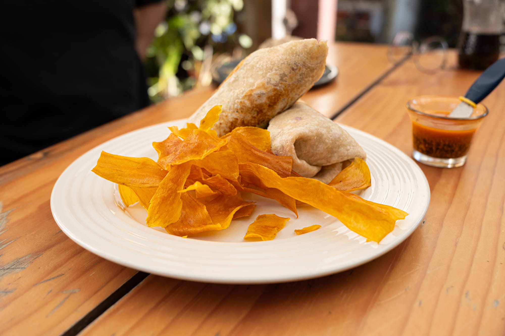 A vegan mushroom mole wrap served with crispy plantain chips and salsa at a café in San Cristóbal de las Casas