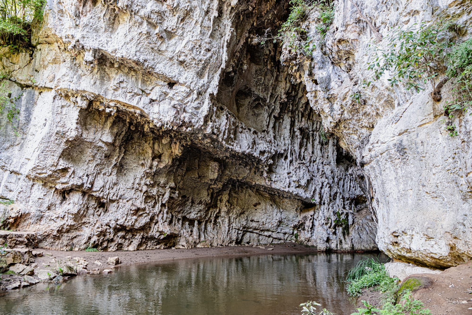 Limestone chamber beneath the natural arch at El Arcotete near San Cristóbal de las Casas, with the río Fogótico pooling along the textured rock walls